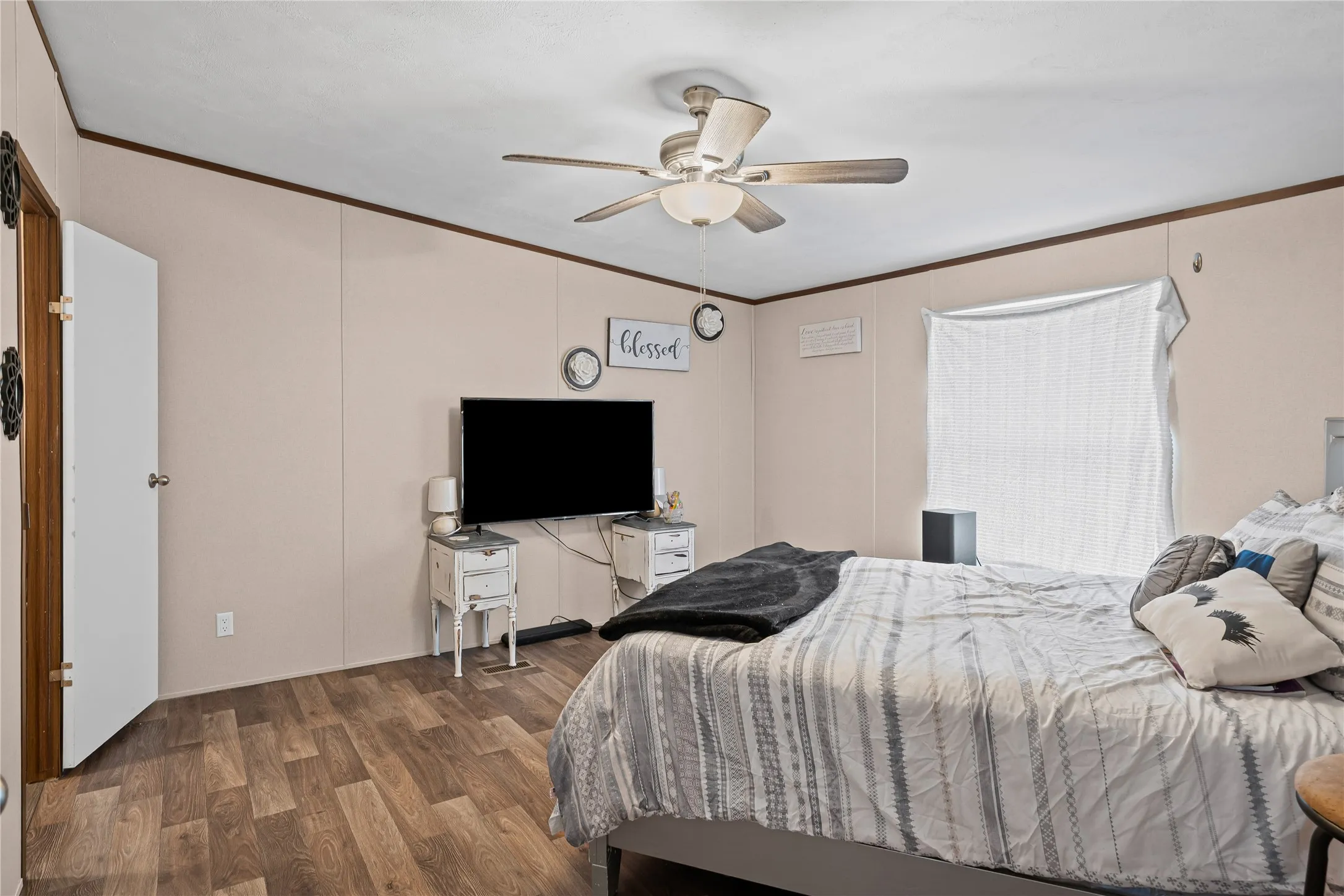 Bedroom with ornamental molding, wood finished floors, and a ceiling fan