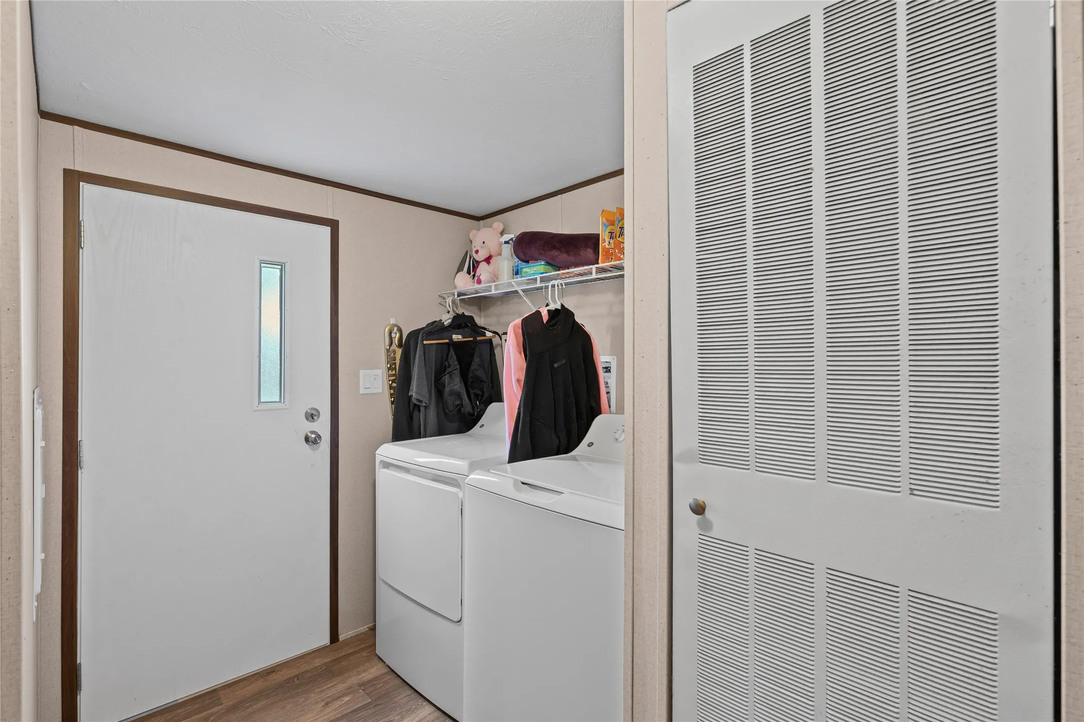 Laundry room featuring a heating unit, light wood-style floors, washer and clothes dryer, and crown molding