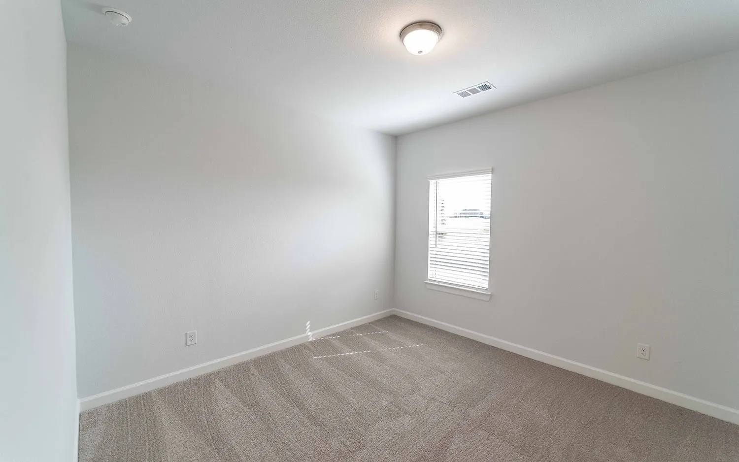 Recessed window with horizontal blinds, neutral wall paint, and gray carpeted flooring
