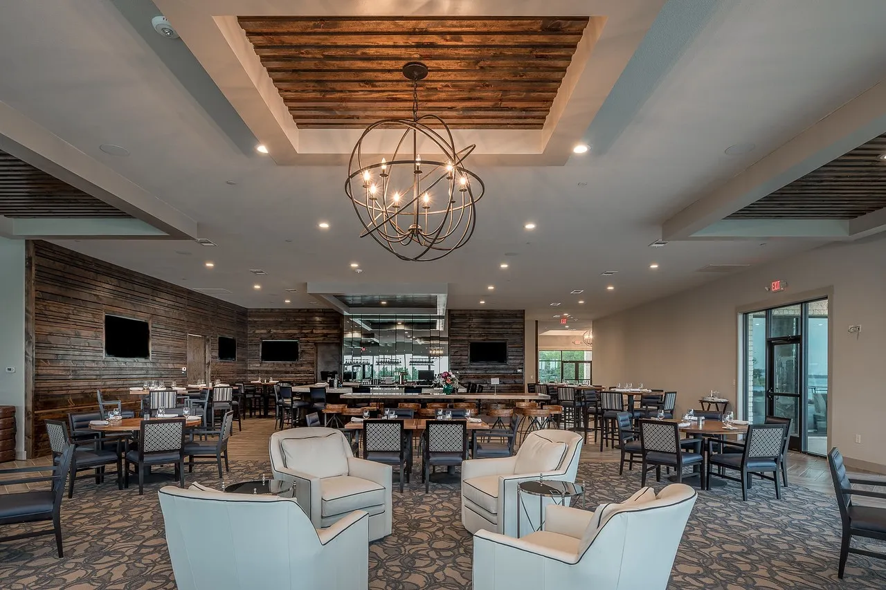 Spacious common area featuring a coffered ceiling with wood-finish panels, recessed lighting, and a prominent spherical chandelier