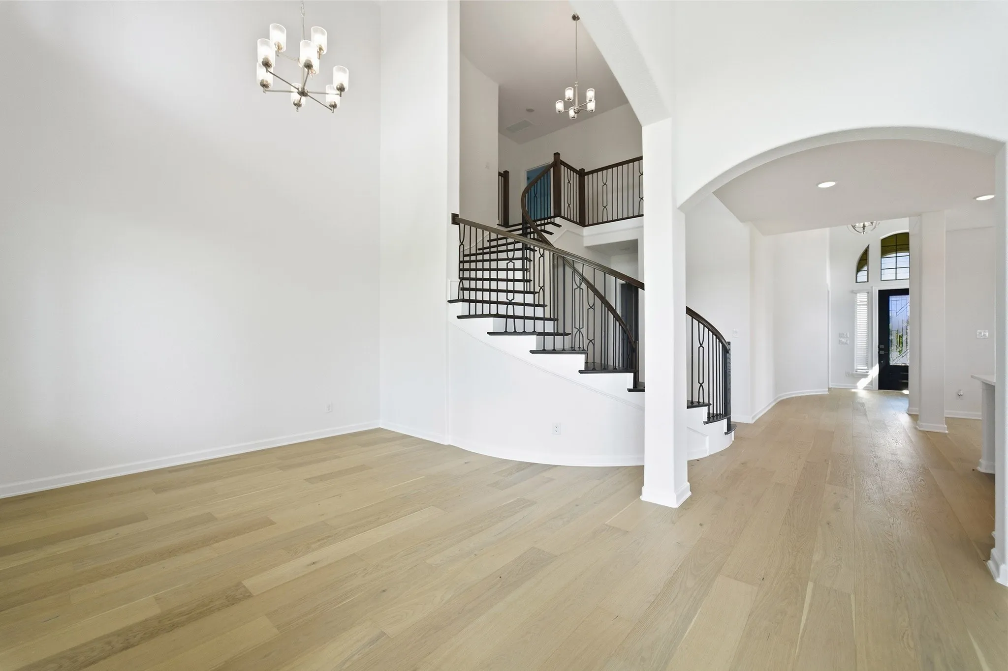 Grand foyer showcasing a curved staircase with wrought iron balusters and rich wood-finish handrails