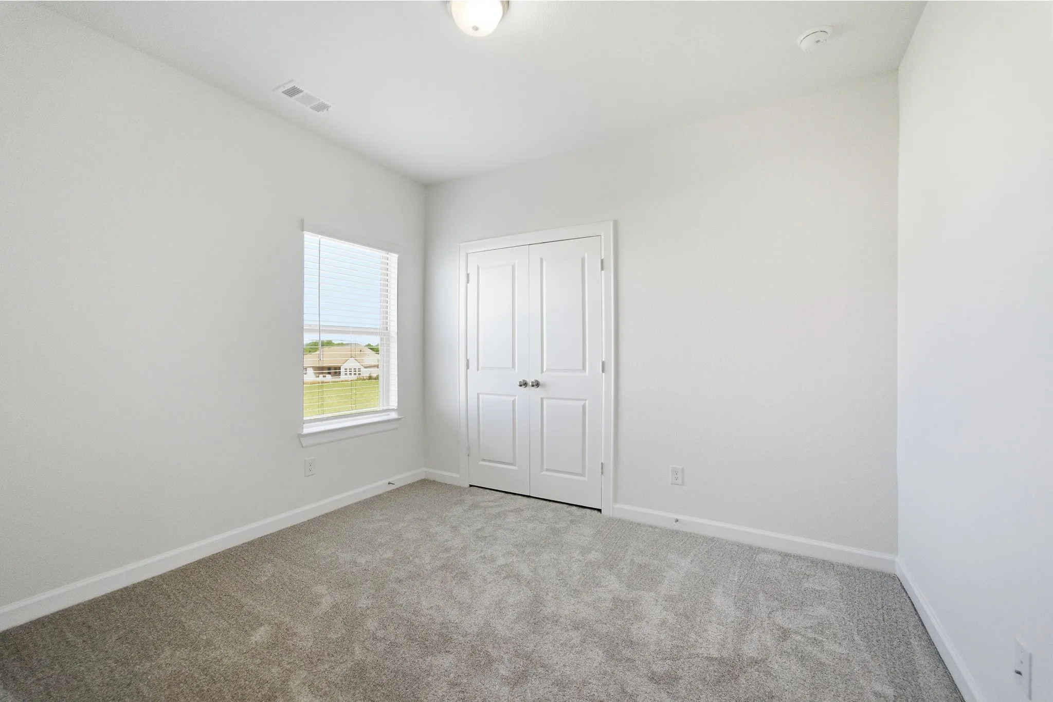 Carpeted room with a double-door closet, a single window, and a flush mount ceiling light fixture