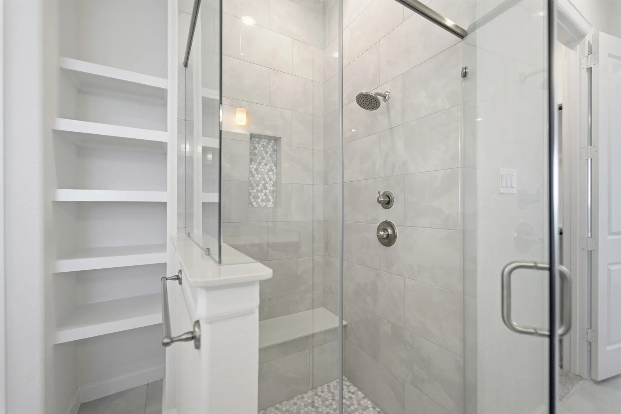 Glass-enclosed shower with a built-in bench, rain showerhead, and brushed nickel fixtures