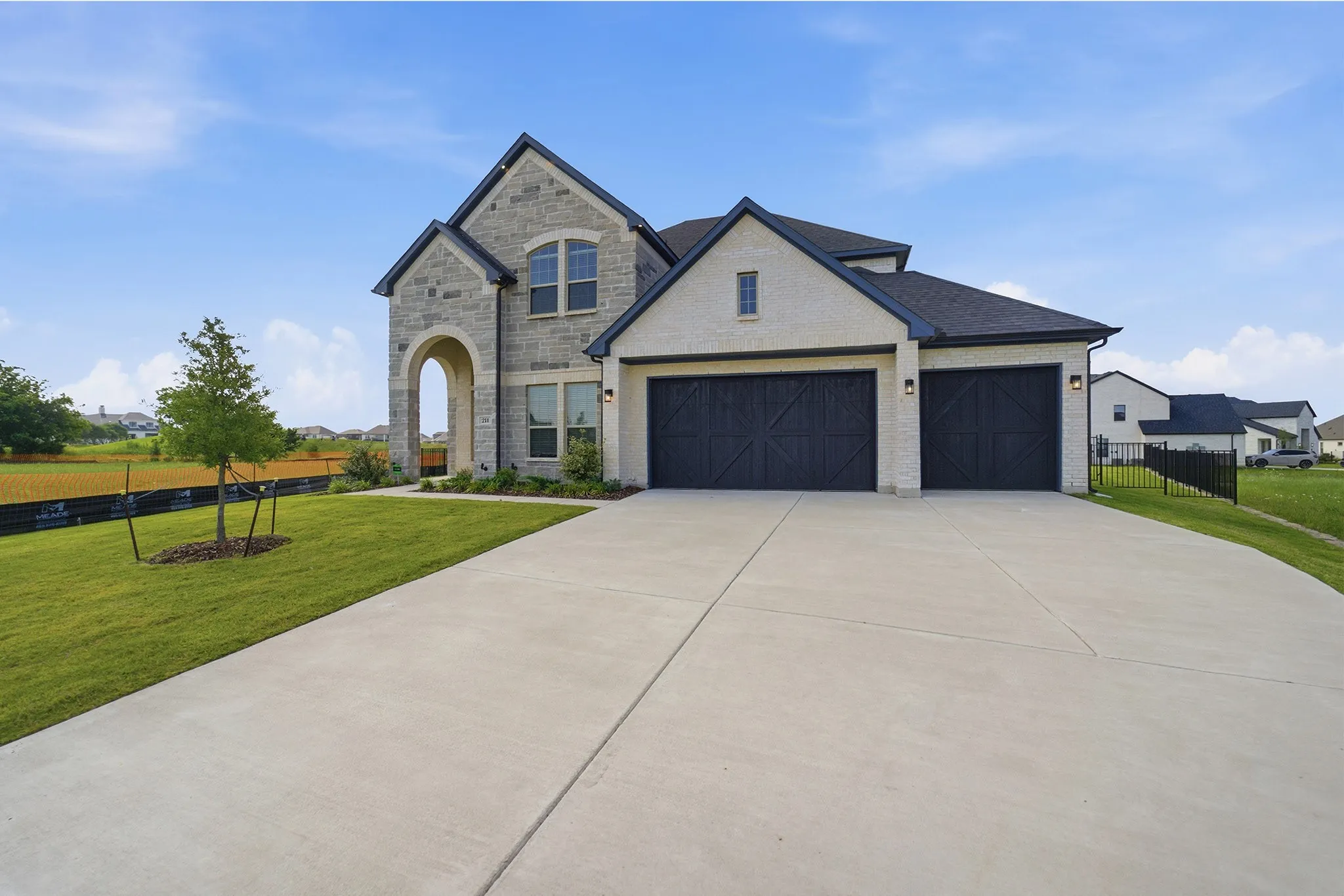 Stone and stucco exterior with dark trim and a prominent arched entryway