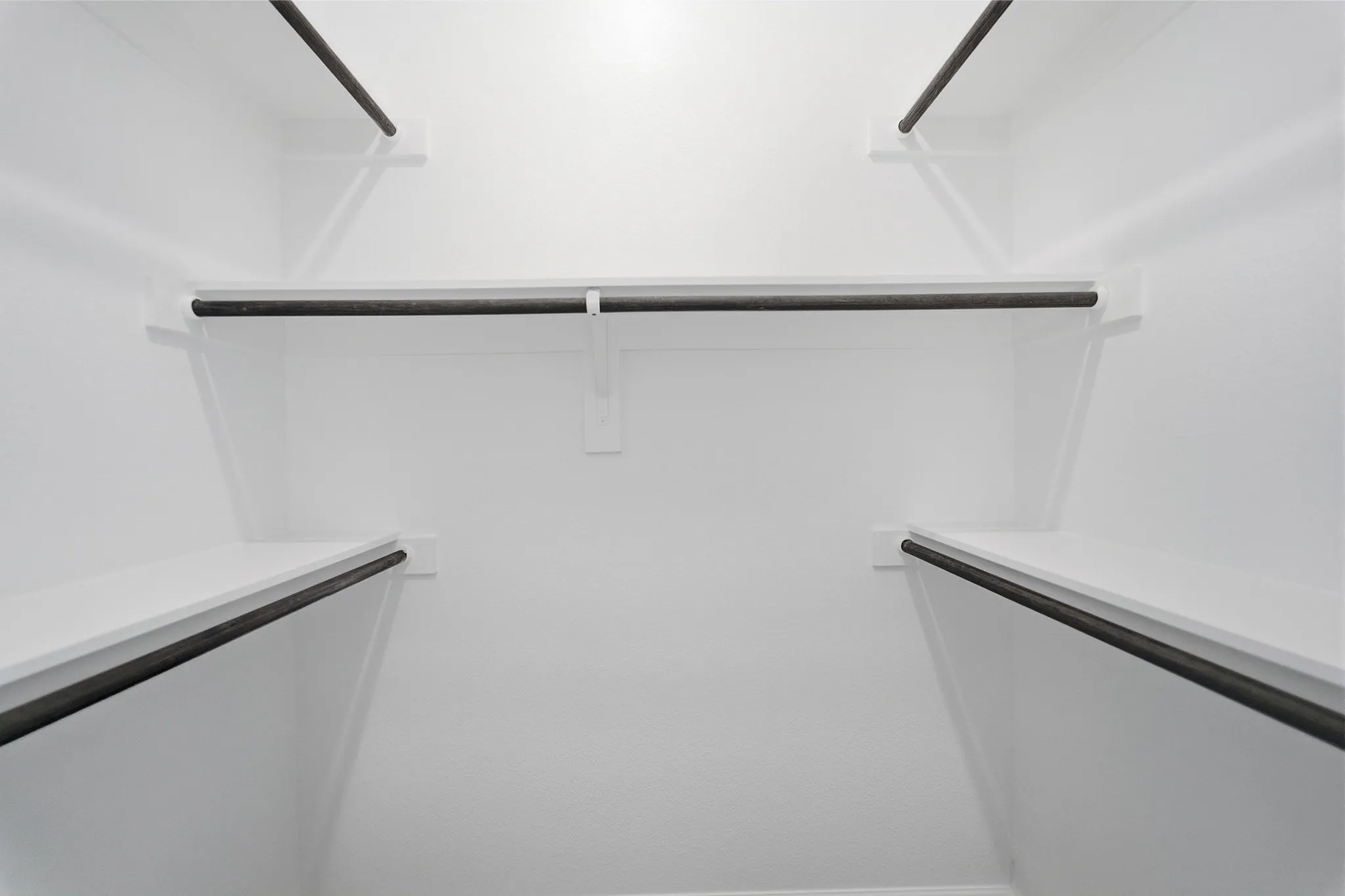 White-painted closet interior featuring multiple shelving units and clothing rods