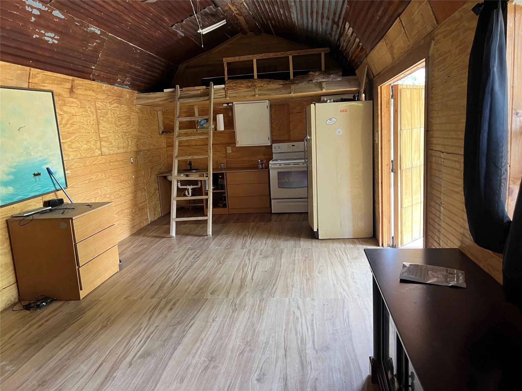 Kitchen featuring white appliances, wood walls, light wood finished floors, lofted ceiling, and wood ceiling