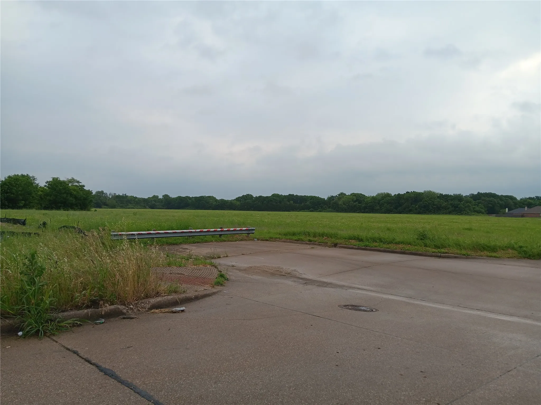 View of concrete street featuring a boat ramp, curbs, and a rural view