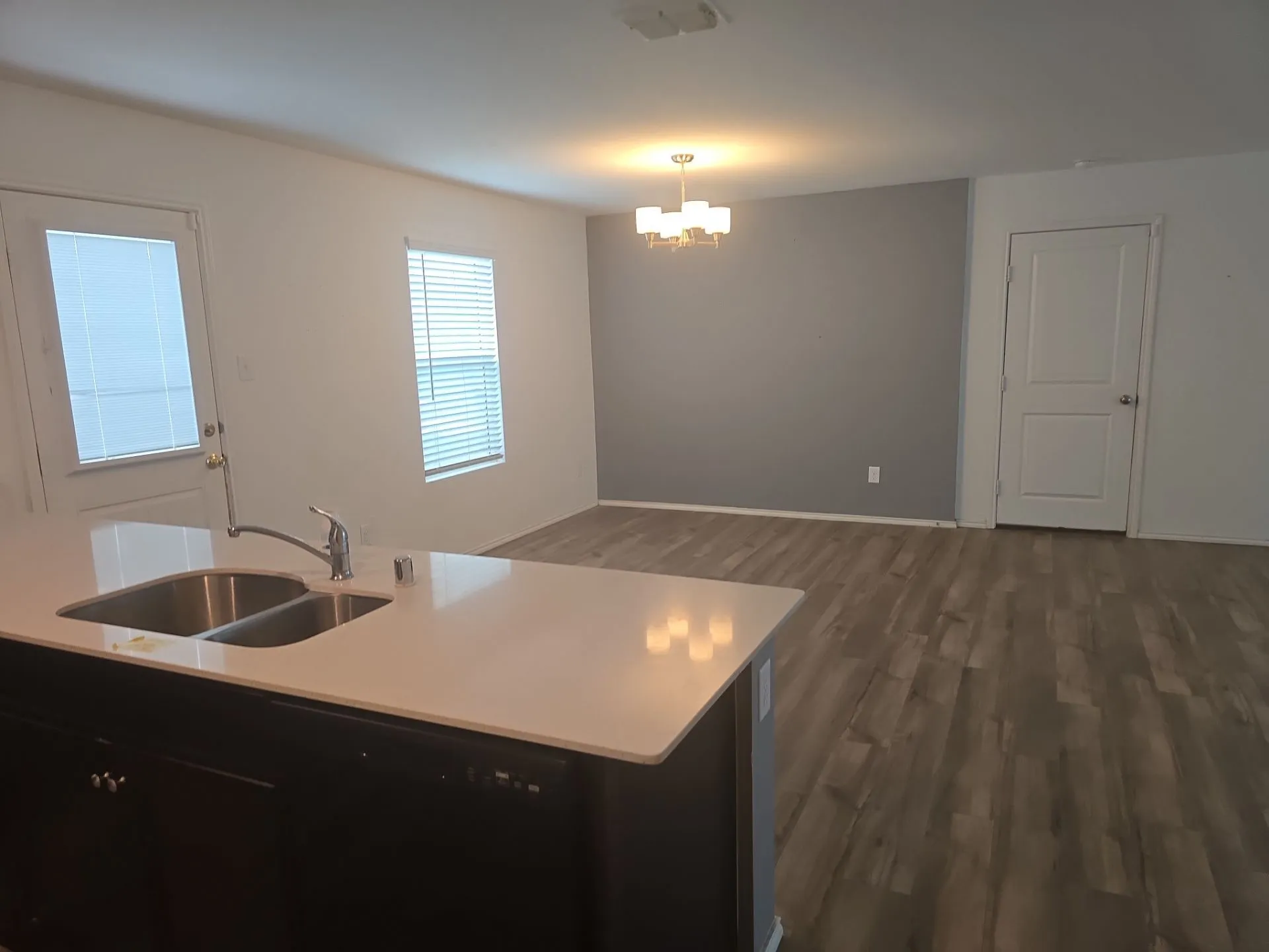 Kitchen with a chandelier, dark wood-type flooring, light countertops, dark cabinets, and decorative light fixtures