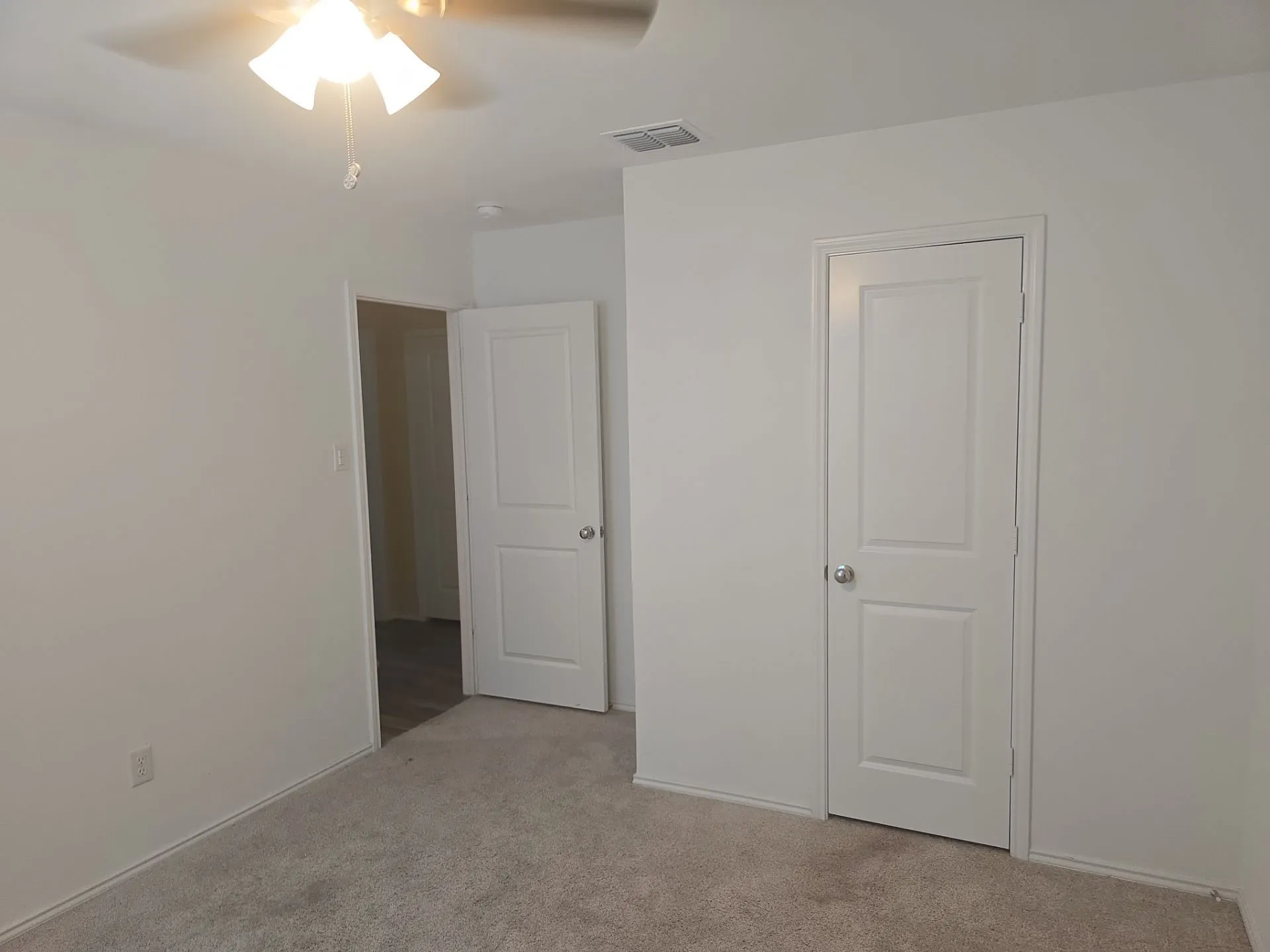 Unfurnished bedroom with light colored carpet and a ceiling fan
