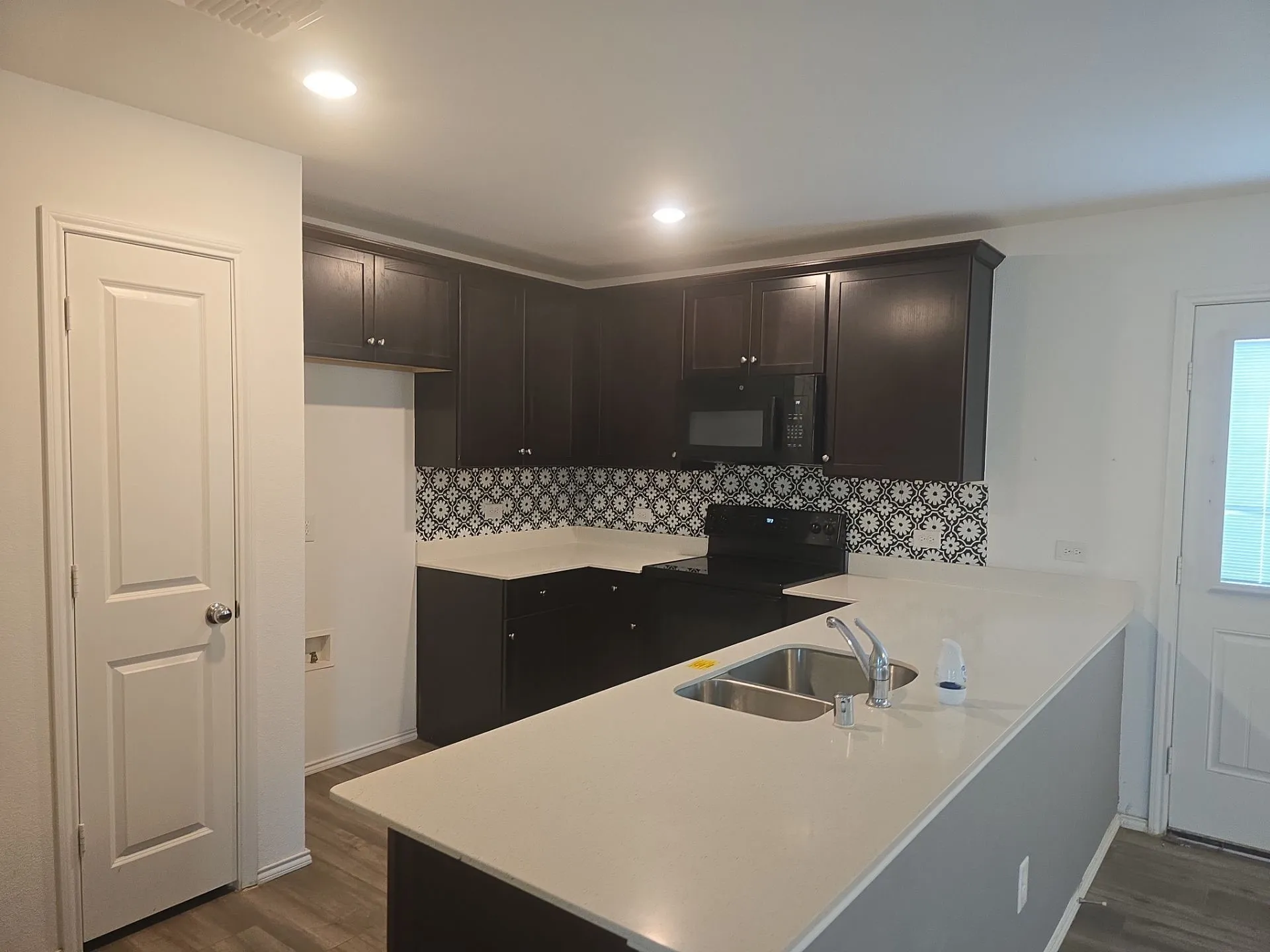 Kitchen with black appliances, dark wood-style flooring, tasteful backsplash, and recessed lighting