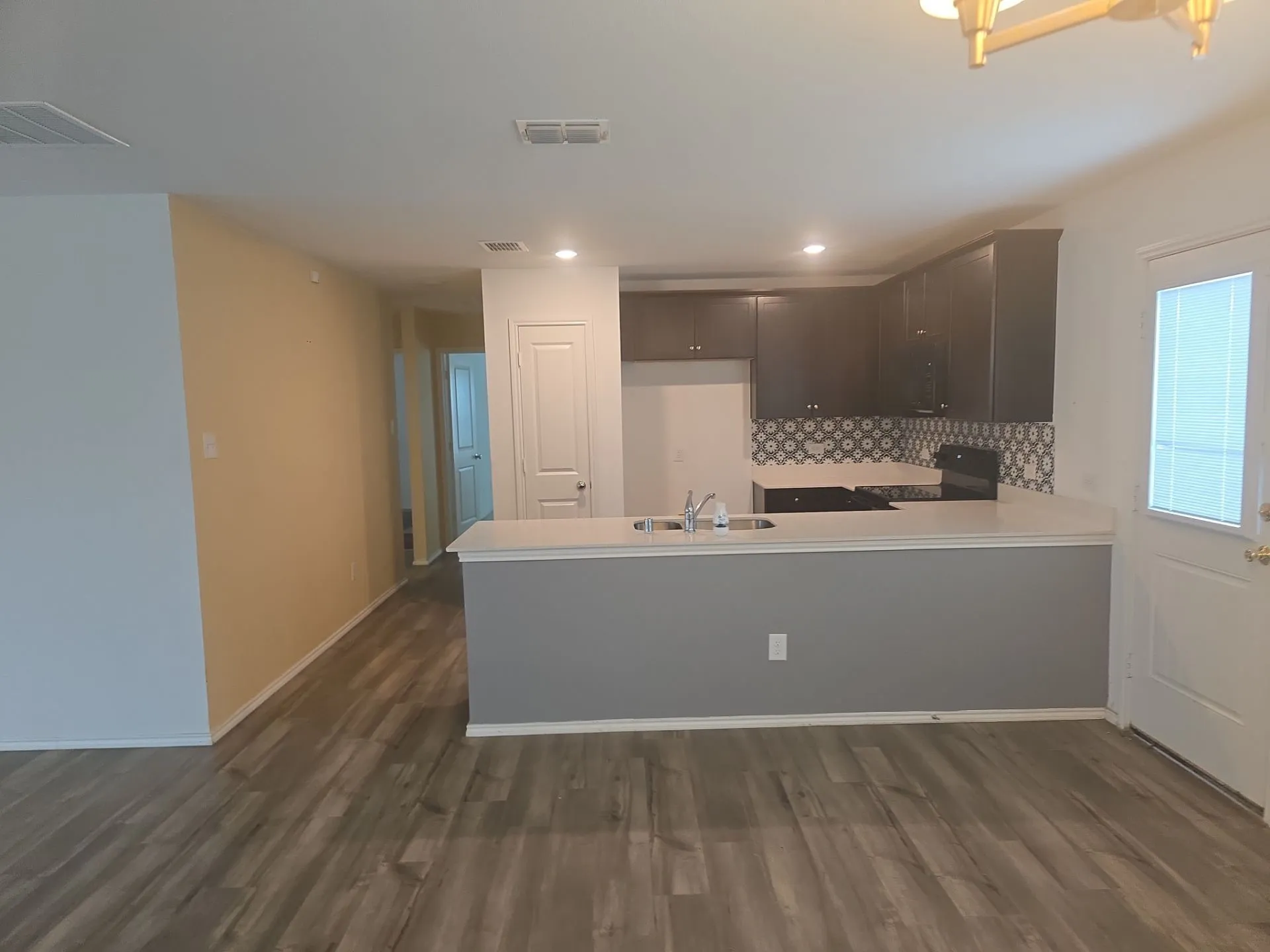 Kitchen with stove, a peninsula, dark wood-style floors, light countertops, and recessed lighting
