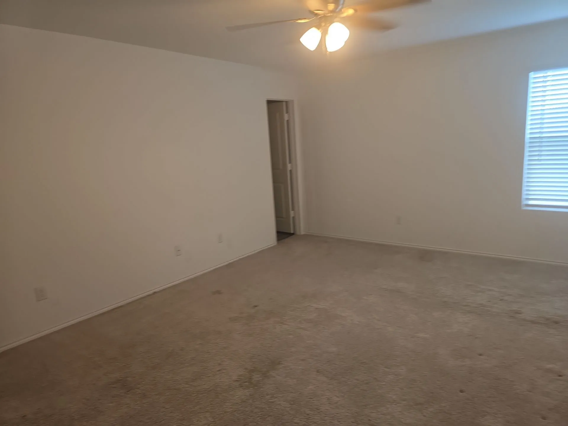 Carpeted spare room featuring ceiling fan and baseboards
