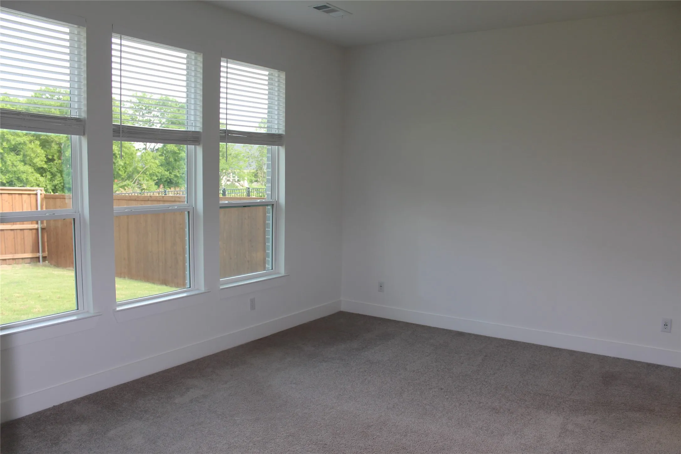 Empty room featuring dark colored carpet and baseboards