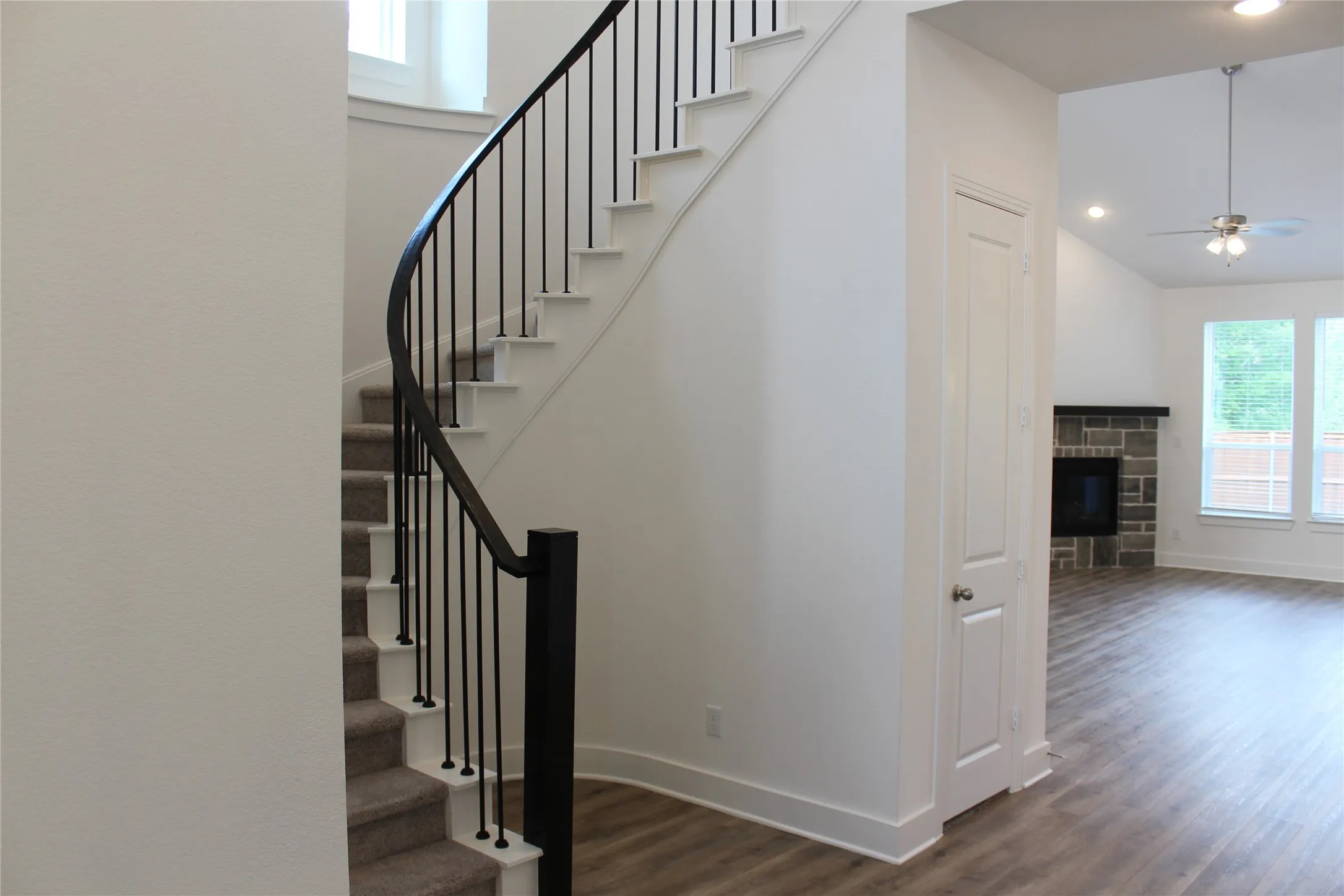 Stairs with wood finished floors, a fireplace, ceiling fan, and recessed lighting
