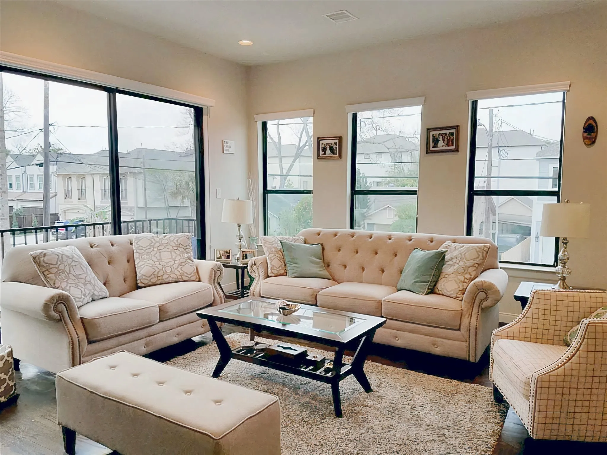 The 2nd floor living room boasts high ceilings and seamlessly connects to the kitchen, bathing the space in abundant natural light. The balcony is accessible from the sliding glass door.