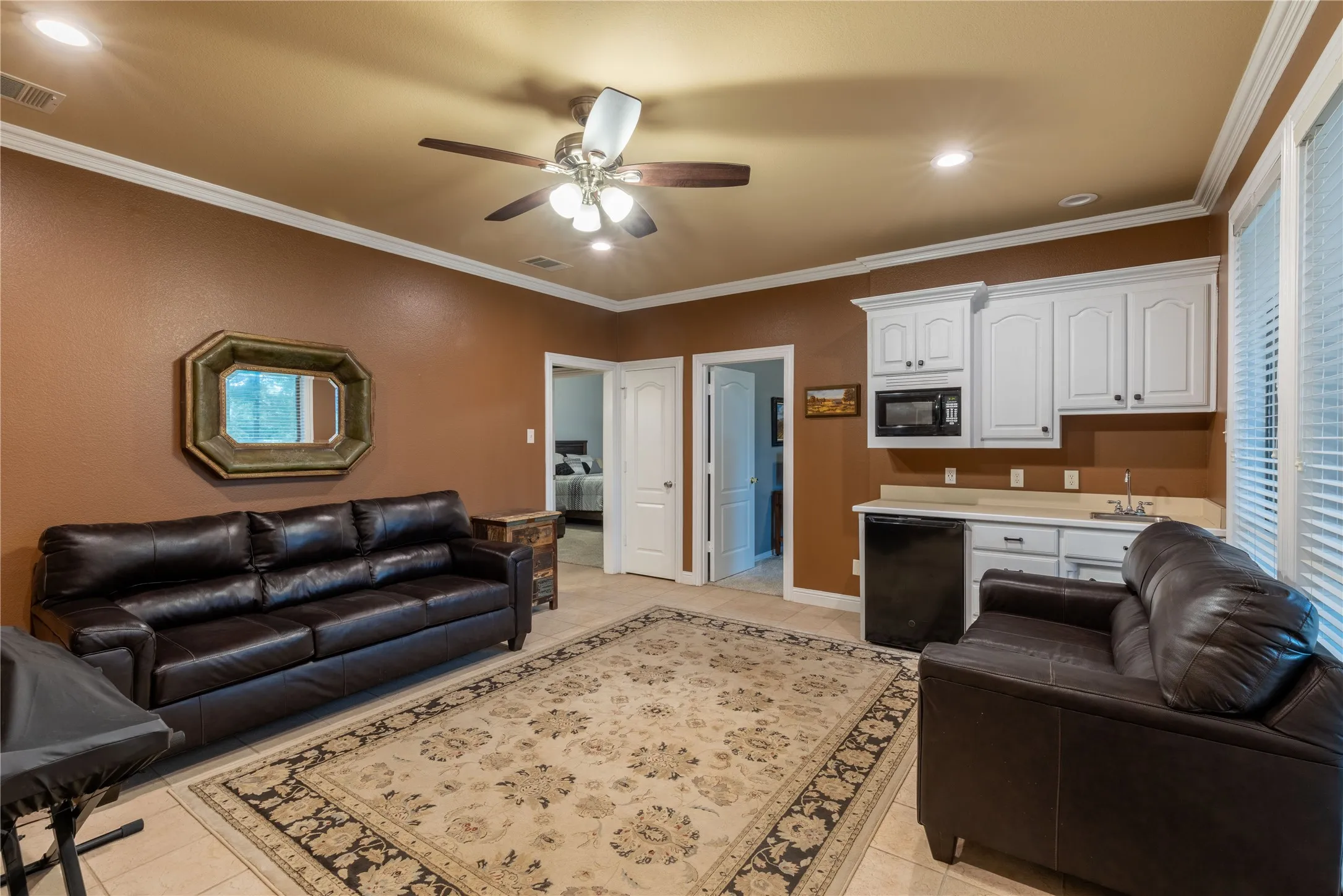 Family room featuring sink, microwave, cabinets, mini fridge, ceiling fan,tile flooring, recessed lighting, ornamental molding