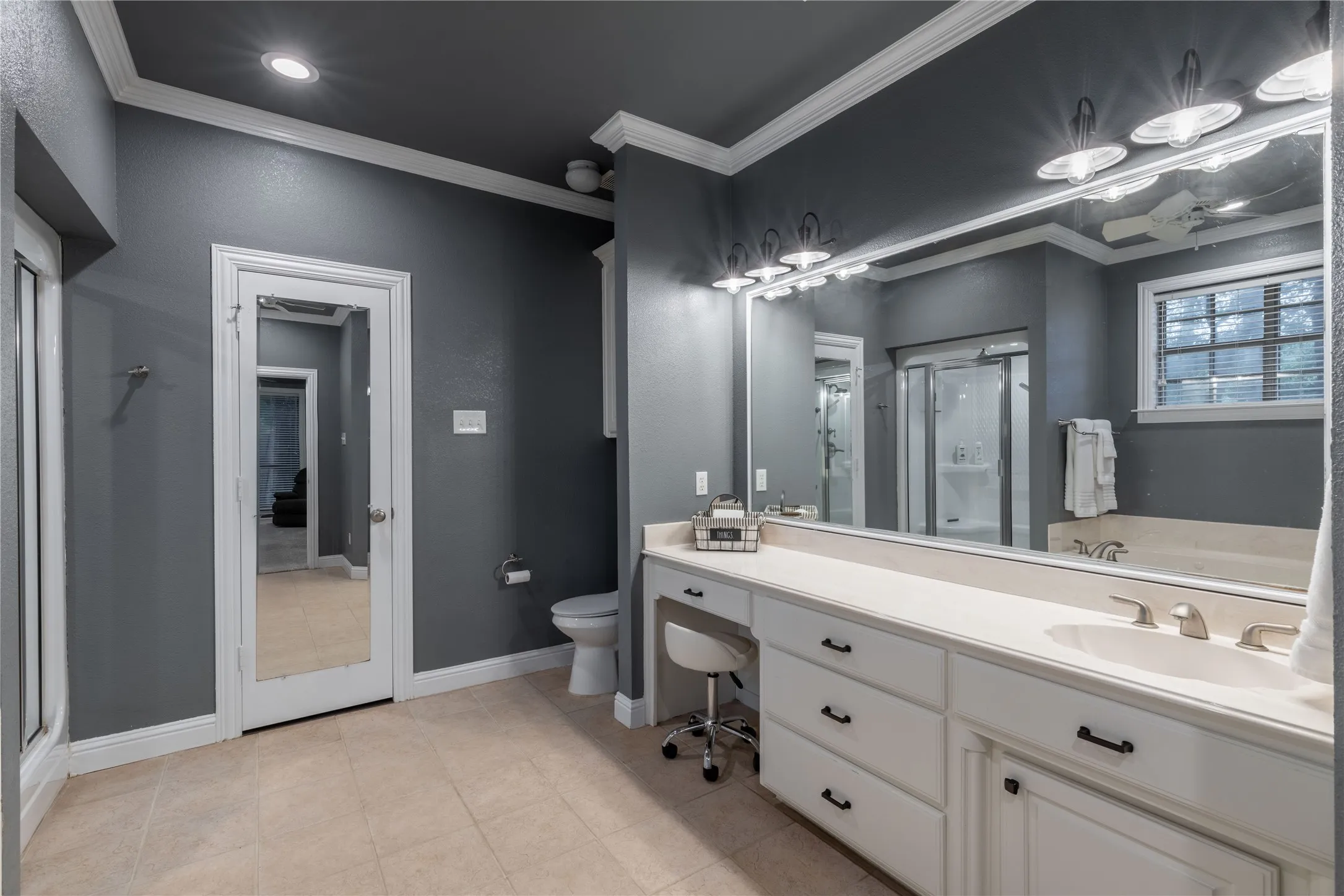 First Primary bathroom with a shower stall, vanity, crown molding, and tile patterned floors