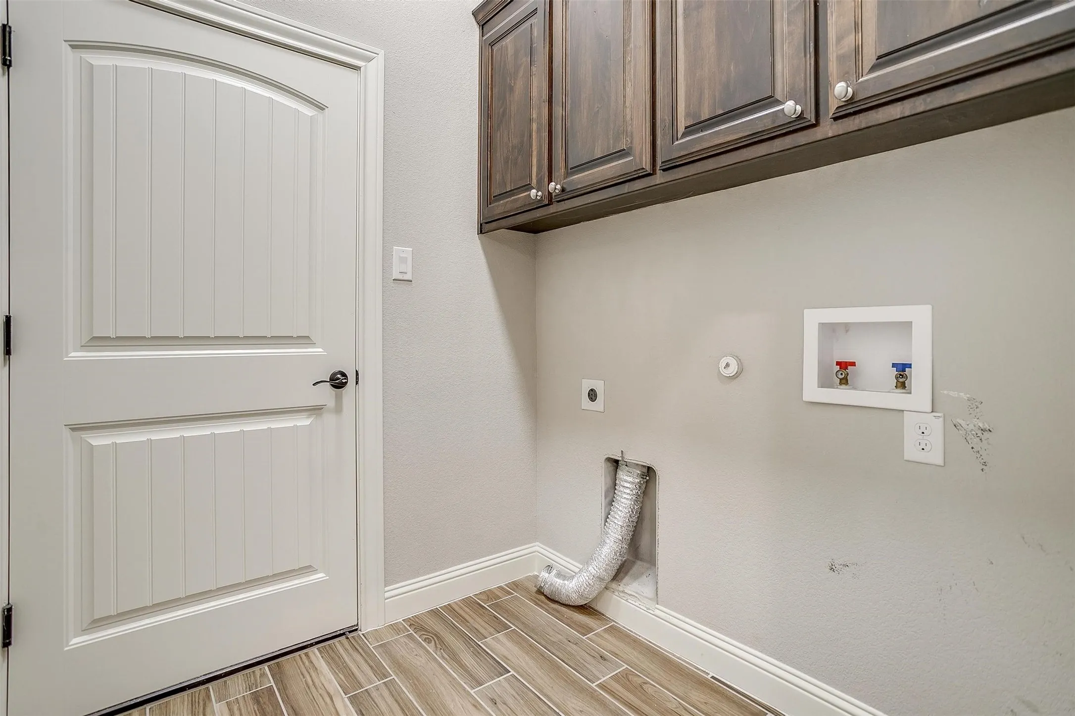 Laundry area featuring hookup for an electric dryer, cabinet space, gas dryer hookup, and wood finish floors