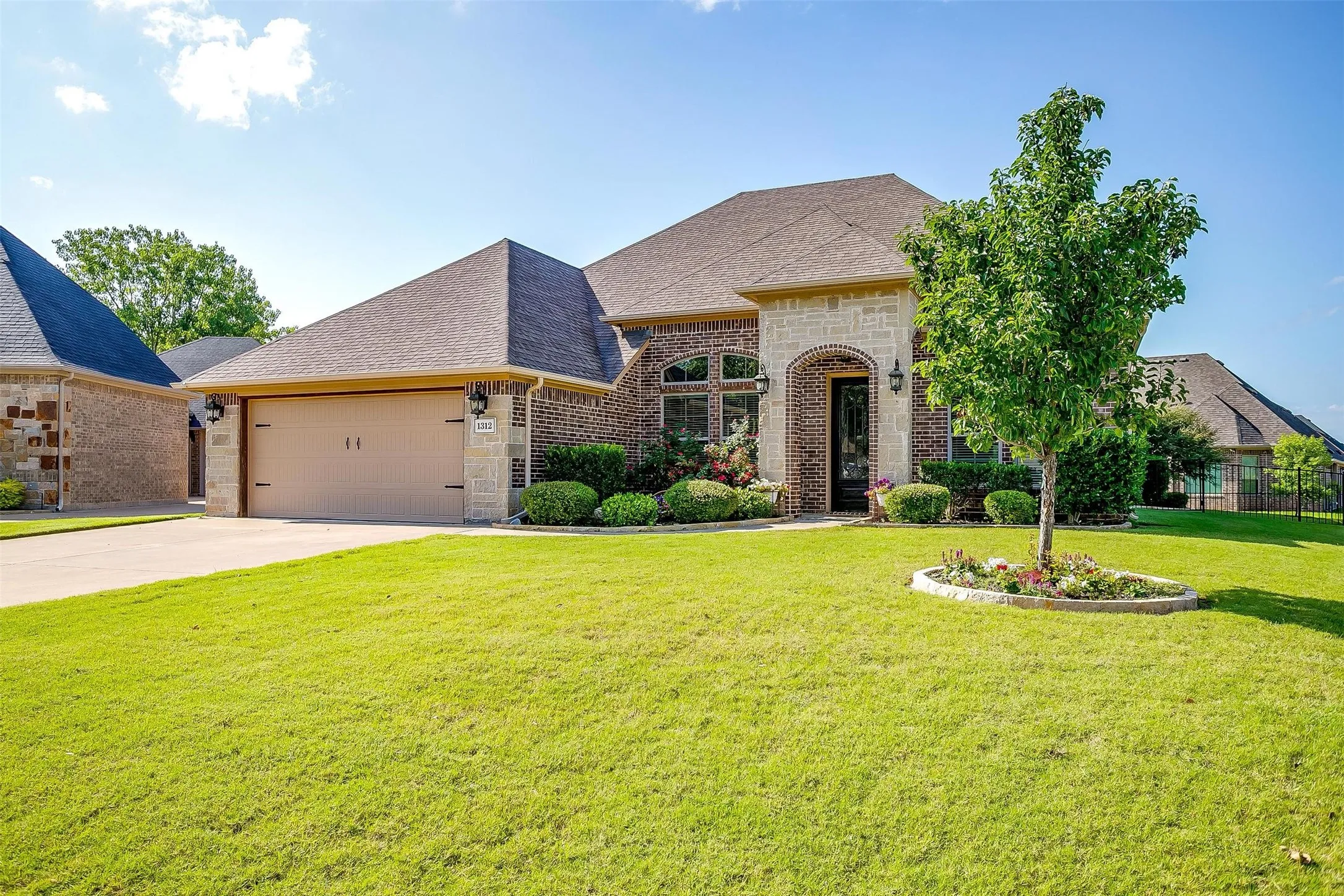 French country home with brick siding, a shingled roof, a garage, and concrete driveway
