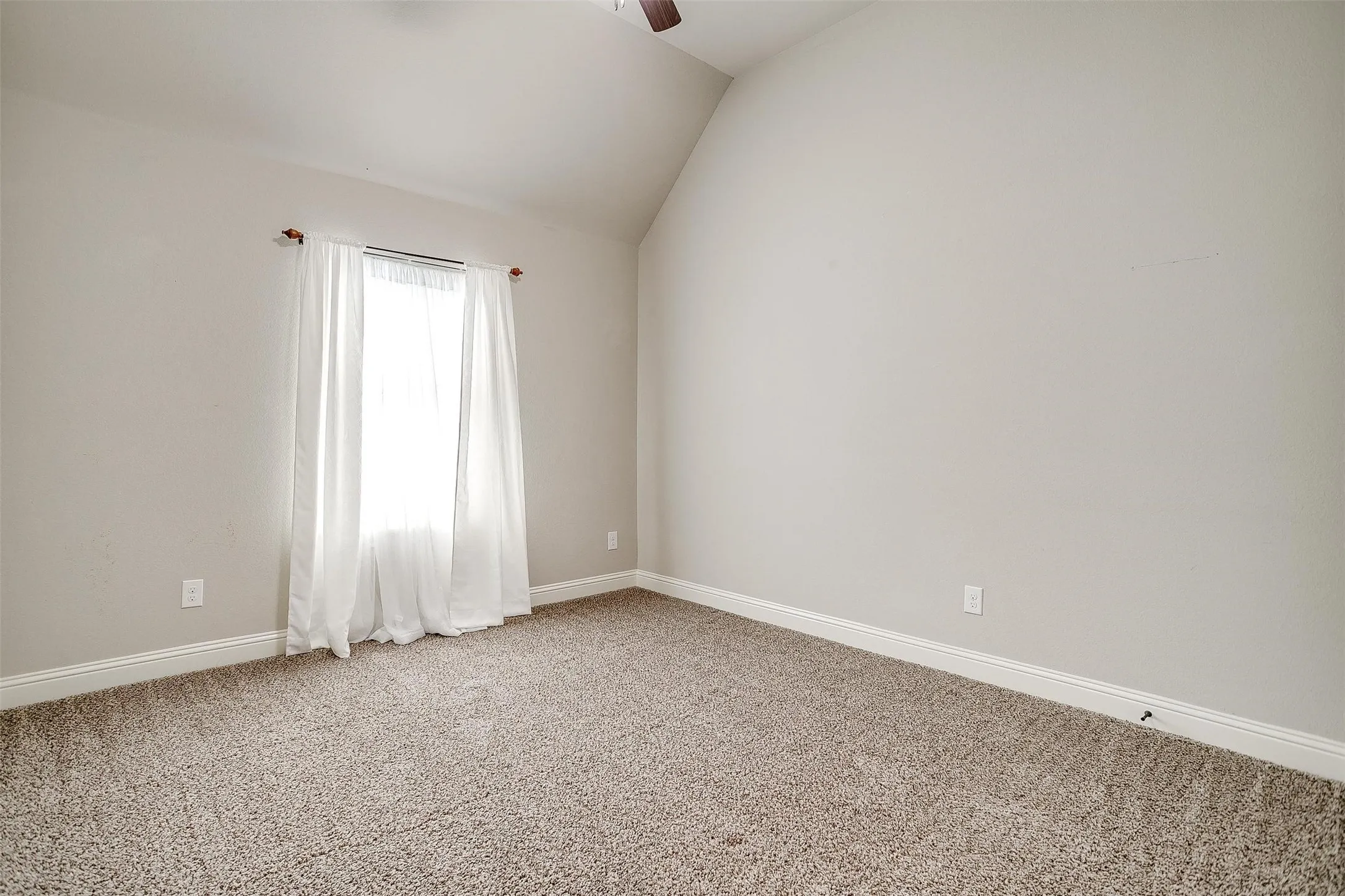 Empty room with lofted ceiling, light colored carpet, and ceiling fan