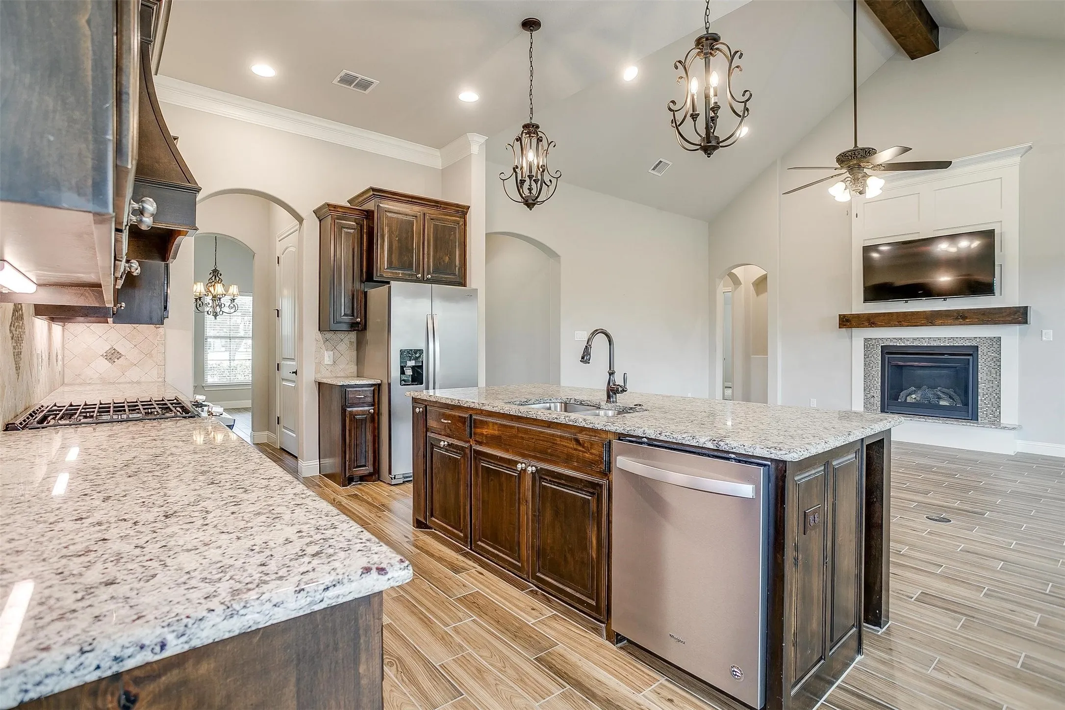 Kitchen with stainless steel appliances, arched walkways, ceiling fan, dark brown cabinets, and wood finish floors