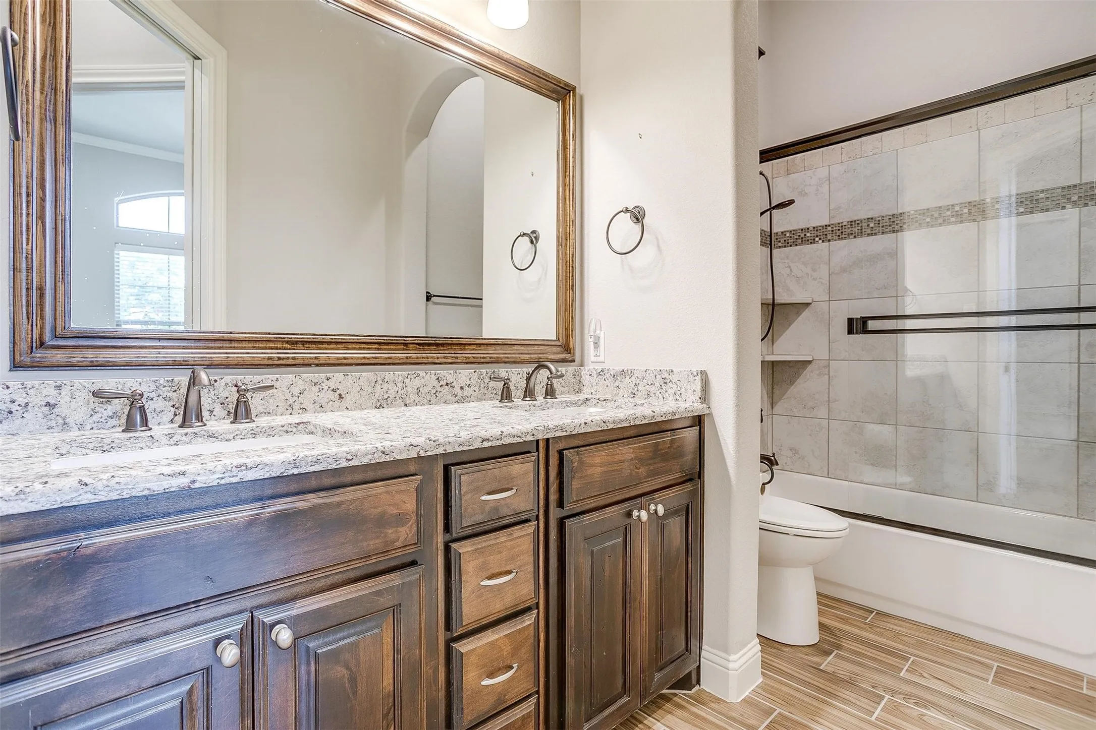 Full bath featuring double vanity, enclosed tub / shower combo, wood tiled floors, and crown molding