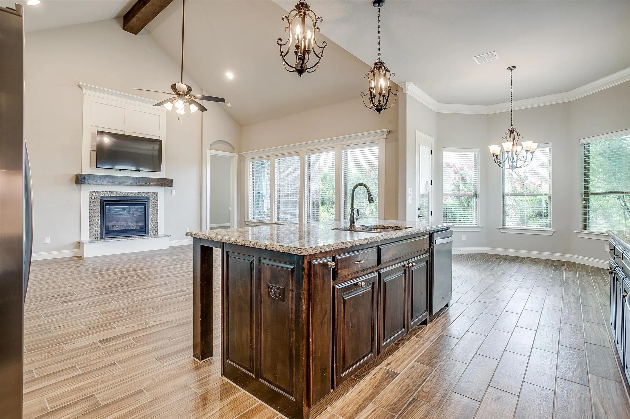 Kitchen featuring a chandelier, stainless steel appliances, light wood-style floors, a glass covered fireplace, and open floor plan