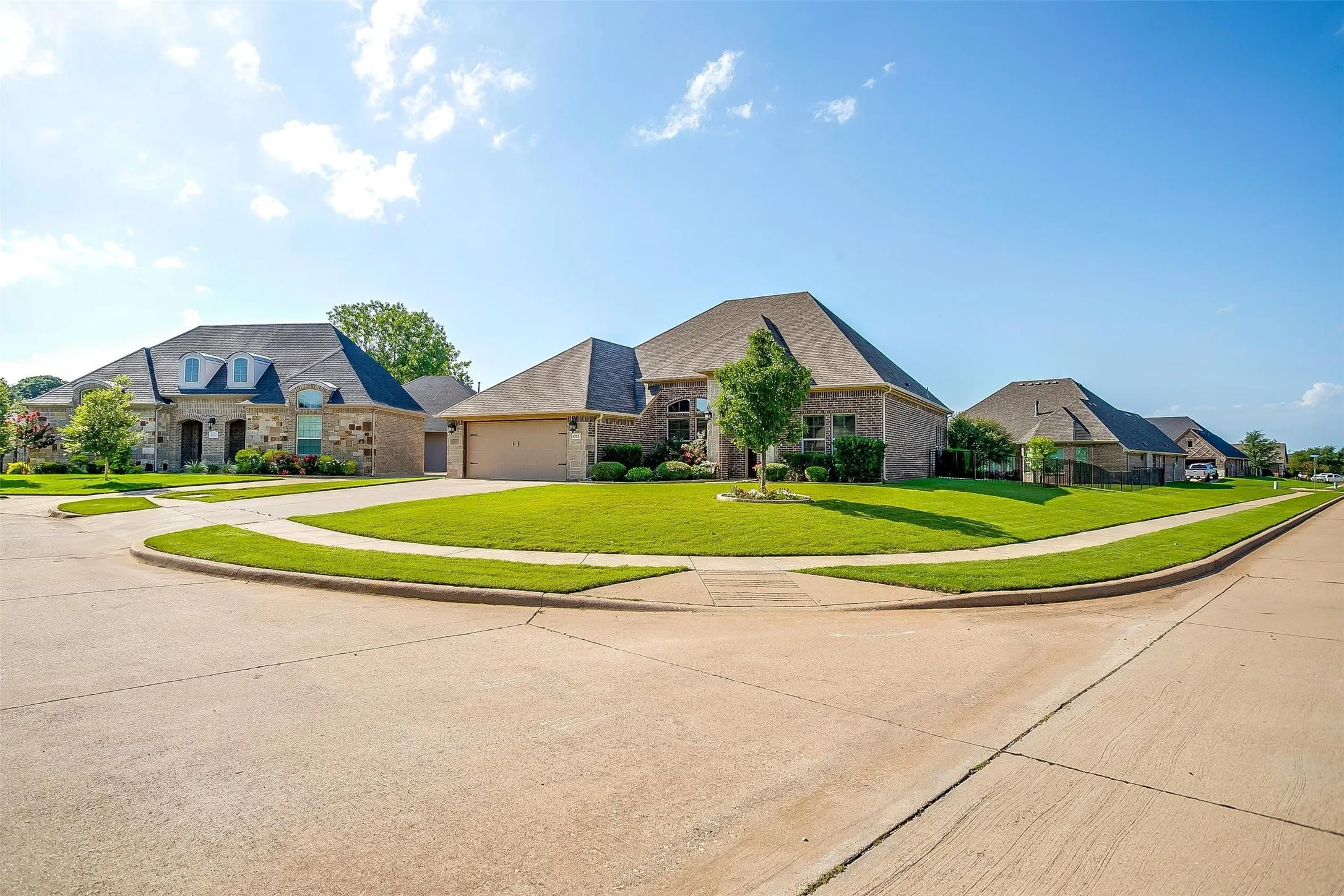 French country style house featuring concrete driveway, brick siding, a front lawn, a residential view, and an attached garage