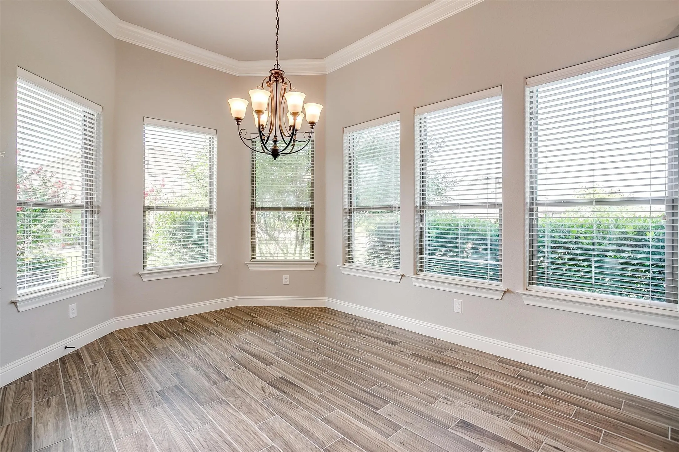 Spare room with plenty of natural light, light wood-style flooring, a chandelier, and crown molding
