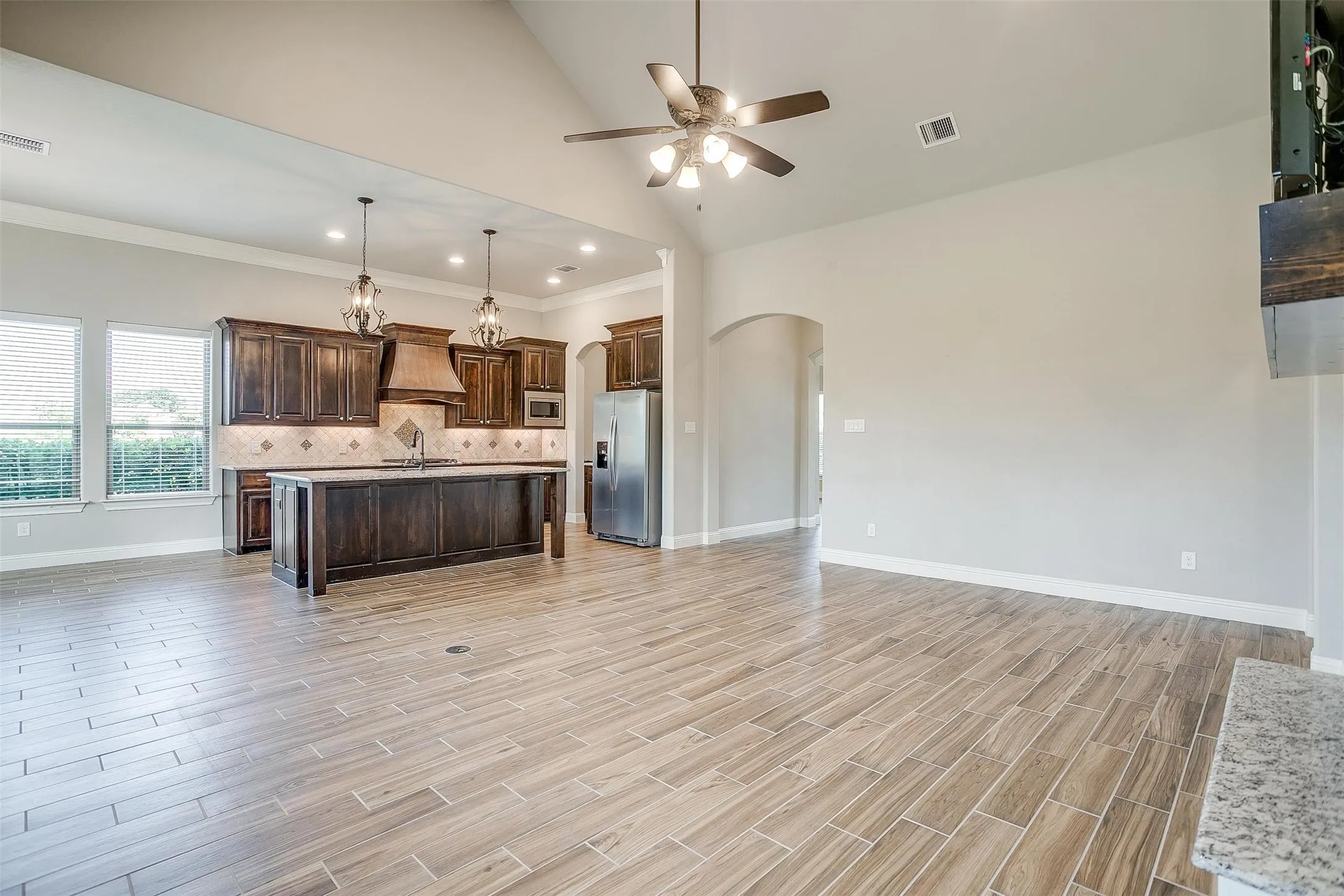 Kitchen with stainless steel appliances, arched walkways, open floor plan, ceiling fan, and crown molding