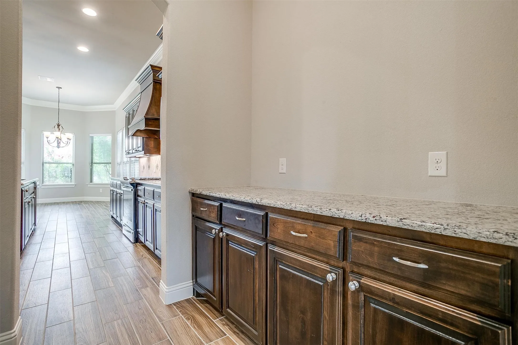 Kitchen featuring stainless steel range oven, a chandelier, crown molding, dark brown cabinets, and premium range hood