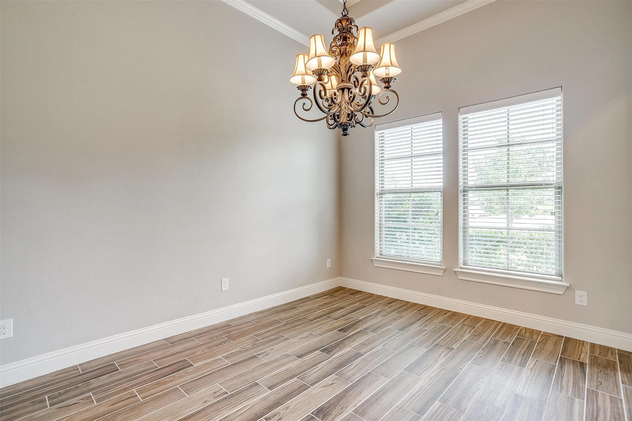 Unfurnished room with a chandelier, light wood-type flooring, and ornamental molding
