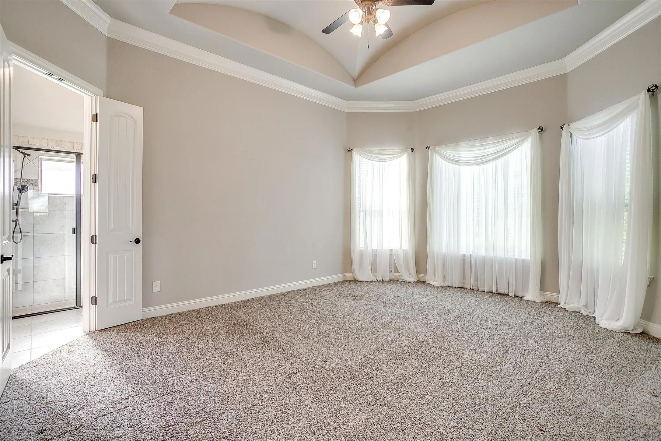 Unfurnished room featuring light carpet, ceiling fan, crown molding, and vaulted ceiling