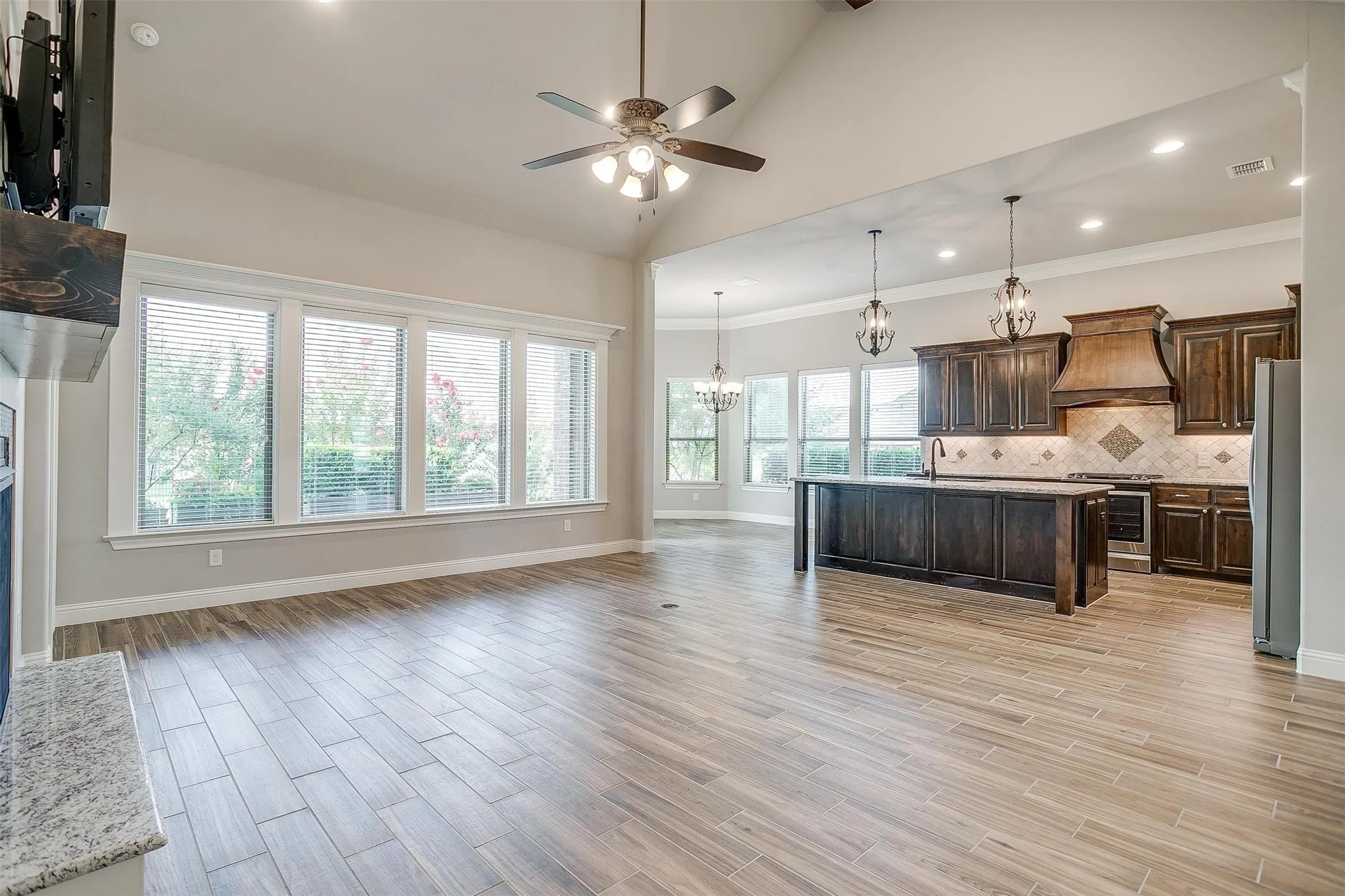 Kitchen with premium range hood, a chandelier, stainless steel stove, freestanding refrigerator, and a ceiling fan