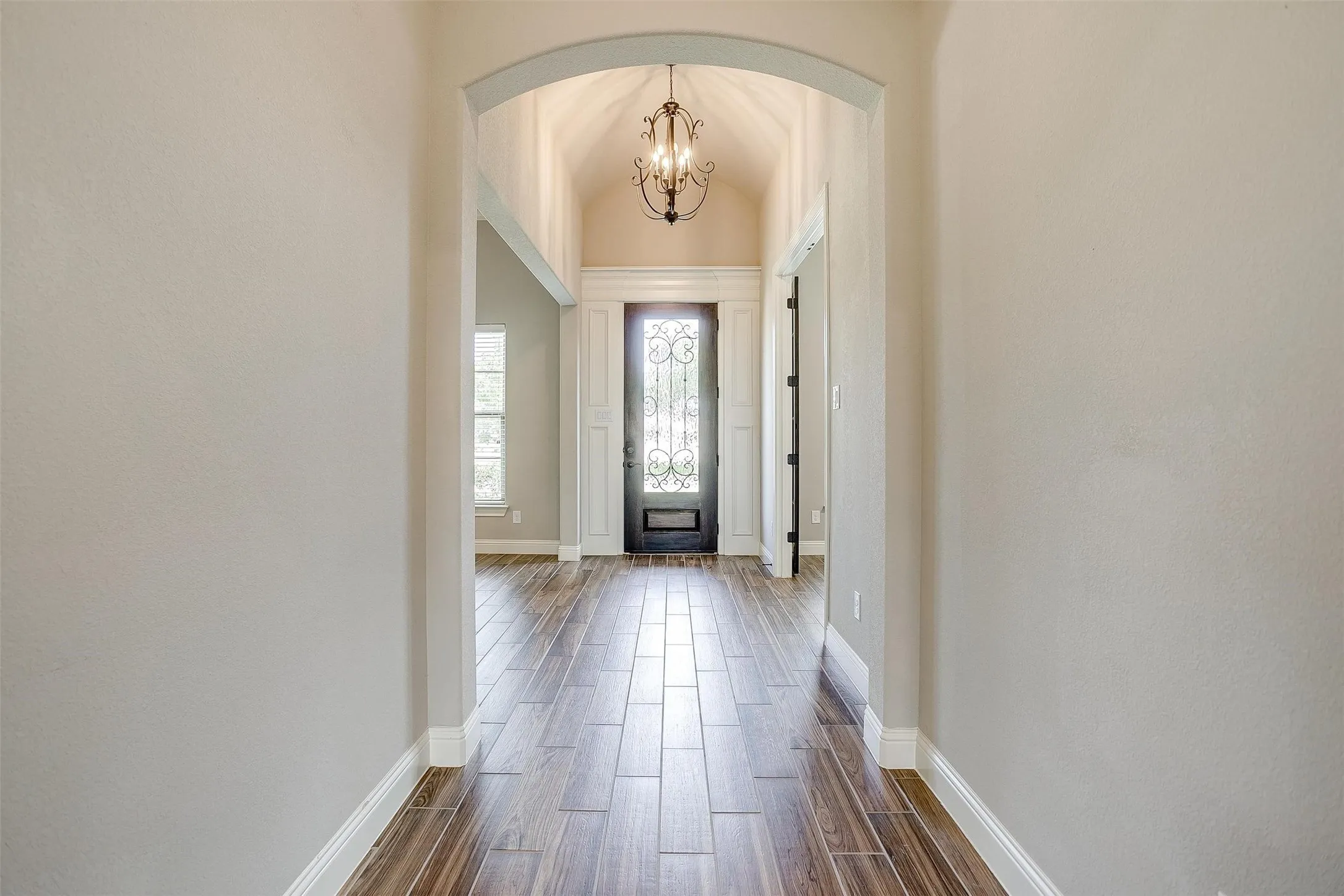 Entryway featuring arched walkways, dark wood-type flooring, and a chandelier