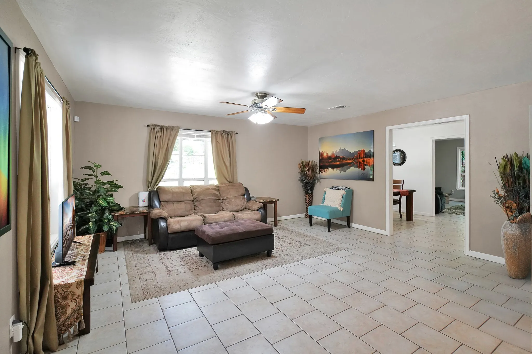 Living area featuring ceiling fan and light tile patterned floors