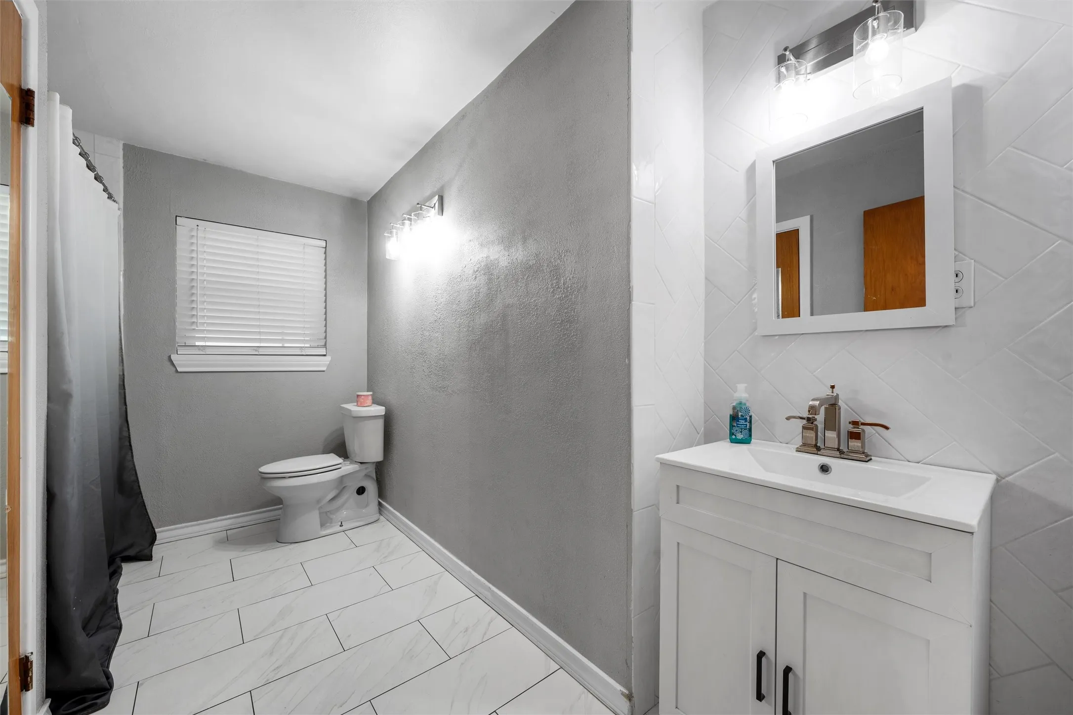 Full bath with vanity and marble look tile flooring