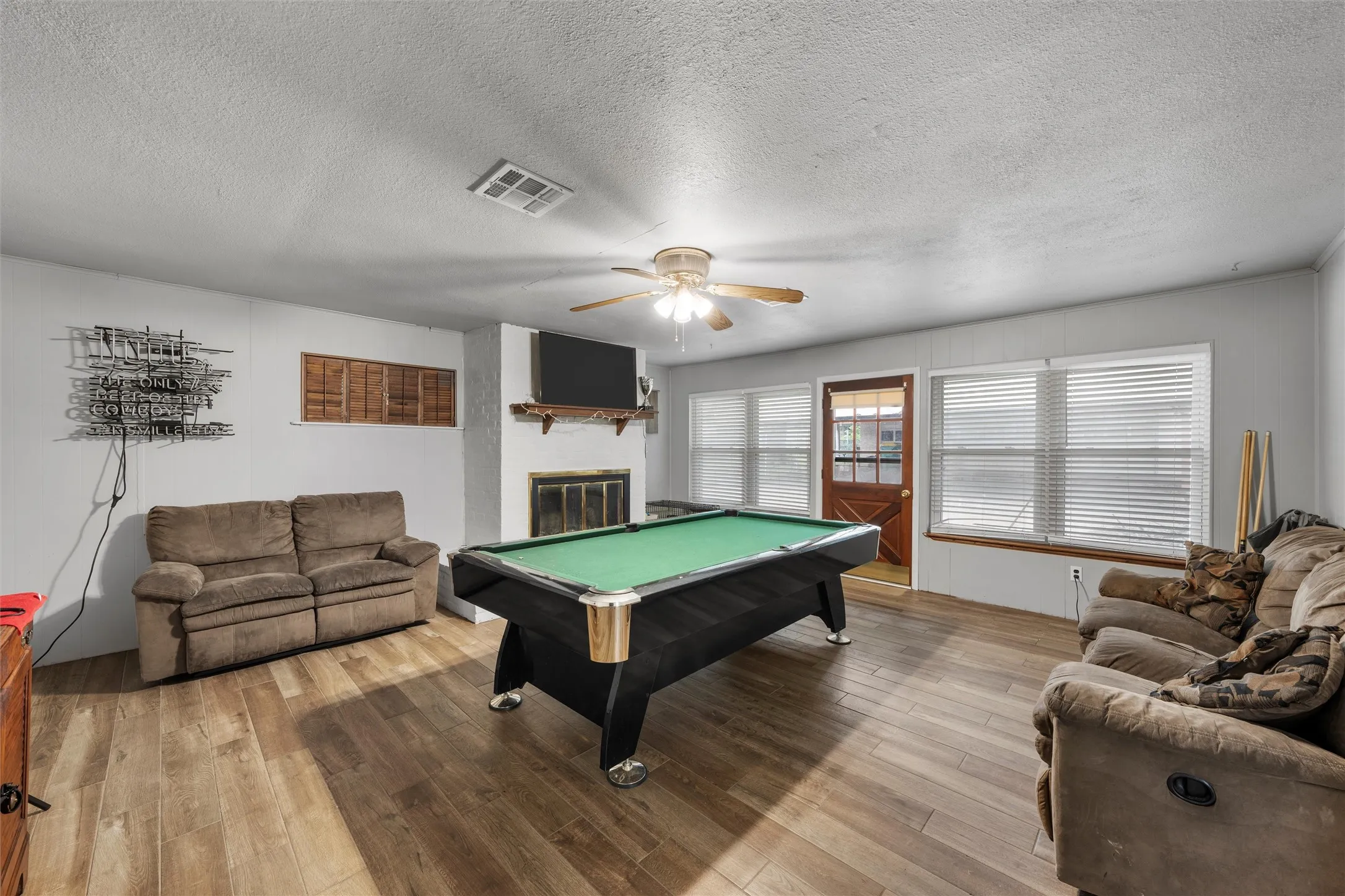 Game room featuring ceiling fan, light wood-style flooring, a textured ceiling, billiards table, and a fireplace