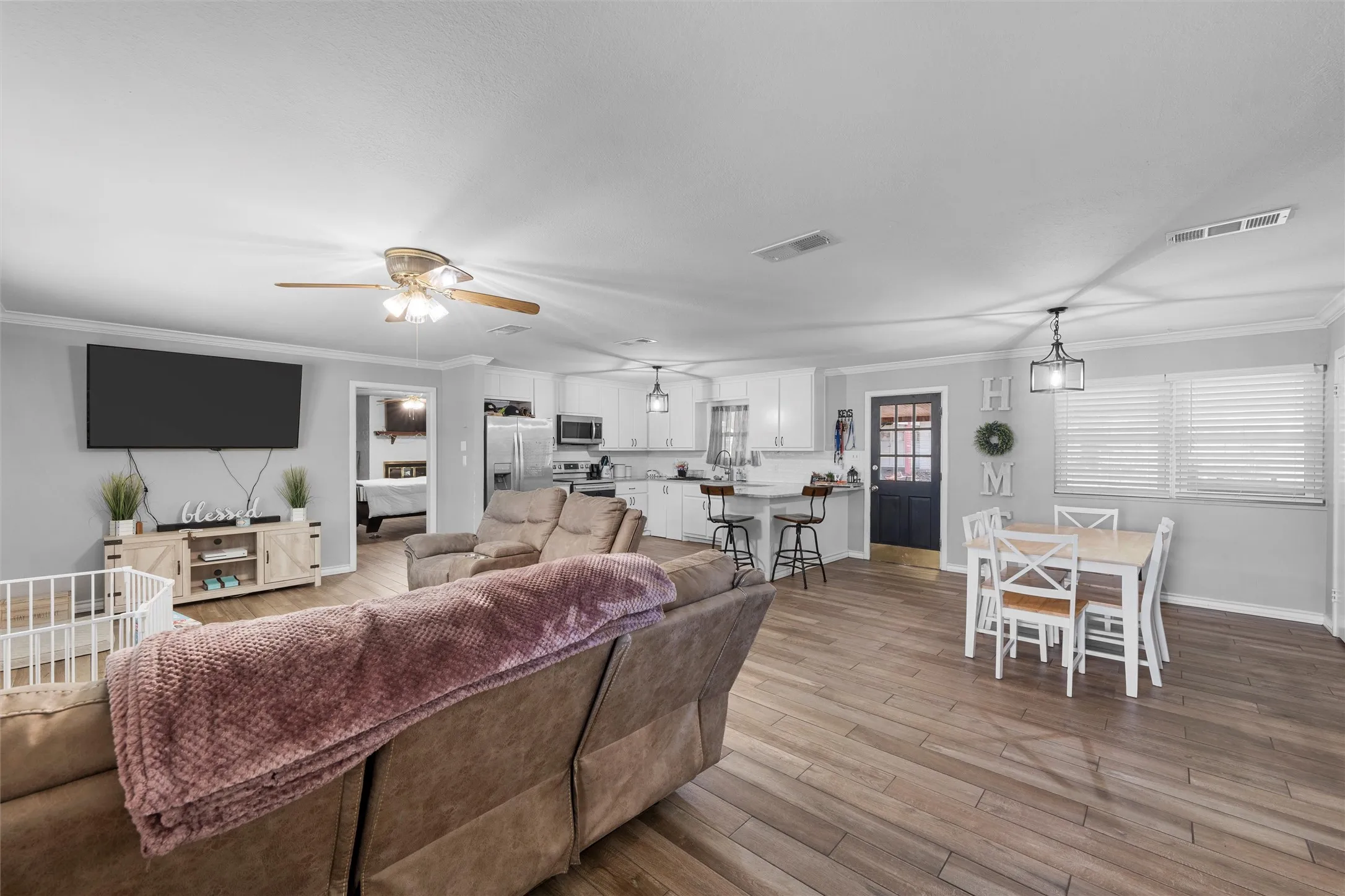 Living room with ceiling fan, ornamental molding, and light wood-type flooring