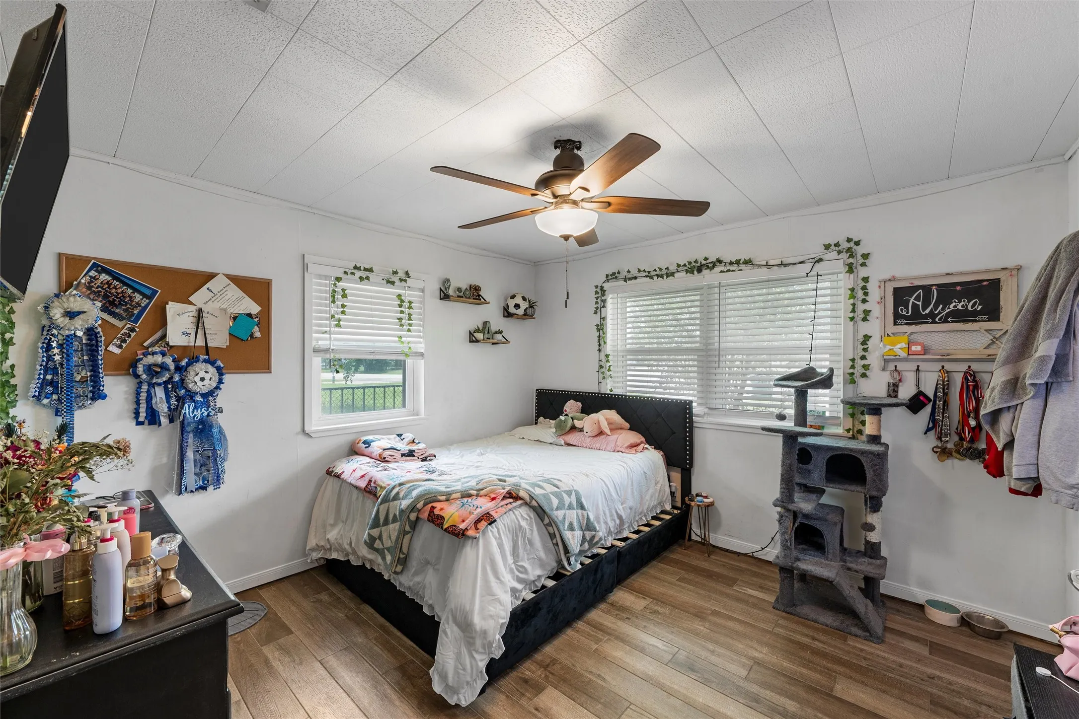 Bedroom with multiple windows, wood finished floors, and ceiling fan