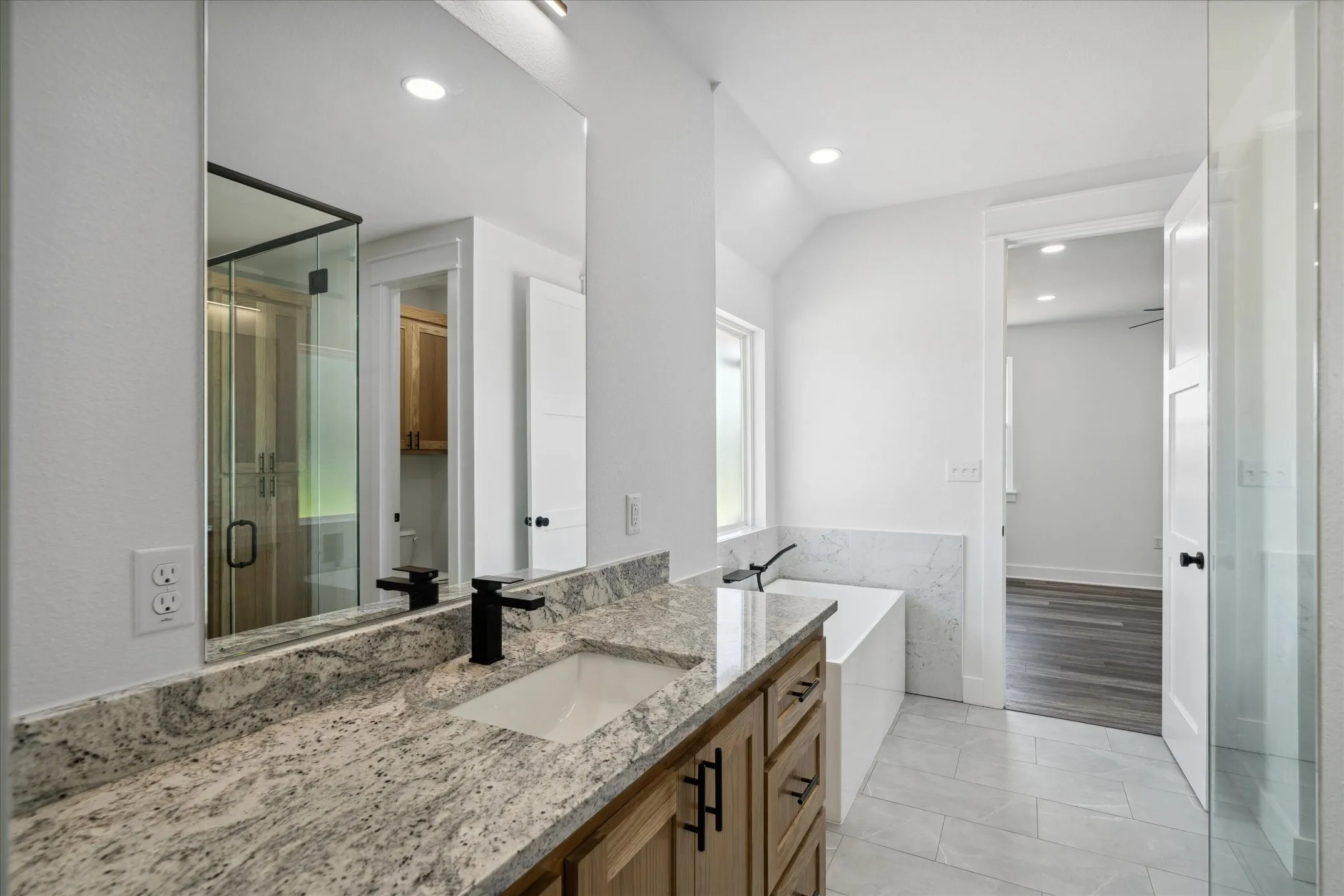 Bathroom with vanity, a bathtub, a stall shower, vaulted ceiling, and recessed lighting