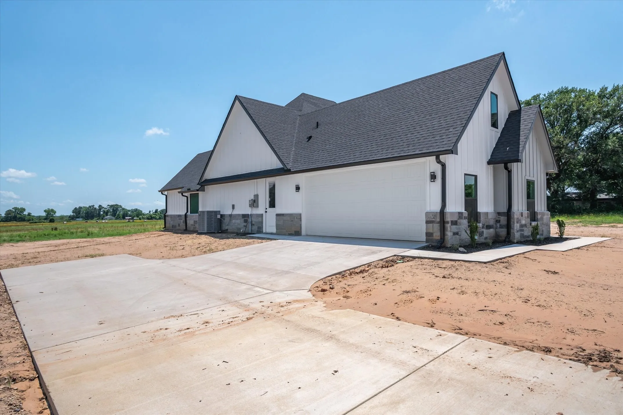 View of home's exterior featuring stone siding, concrete driveway, a shingled roof, and a garage