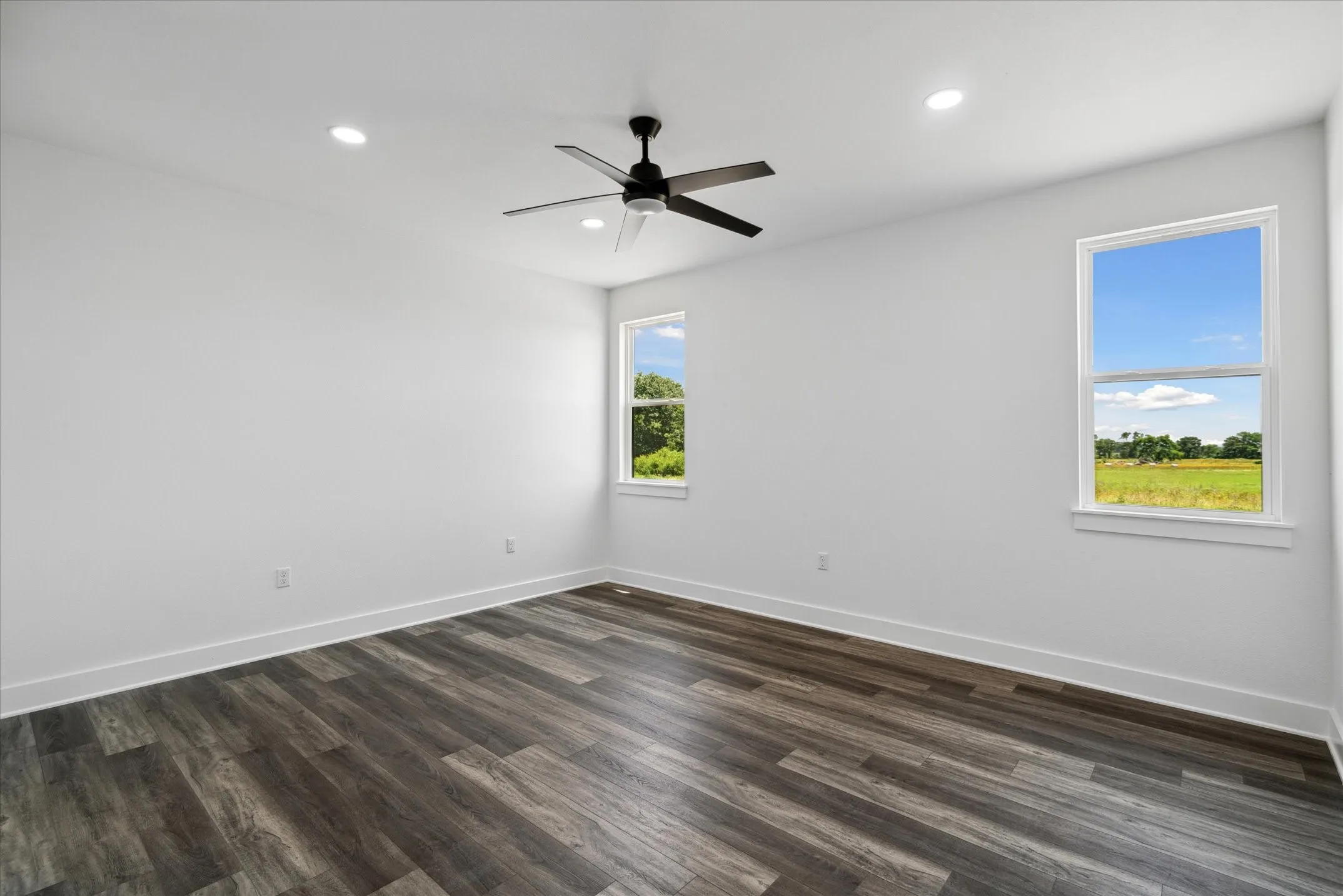 Empty room featuring a ceiling fan, recessed lighting, and dark wood-type flooring