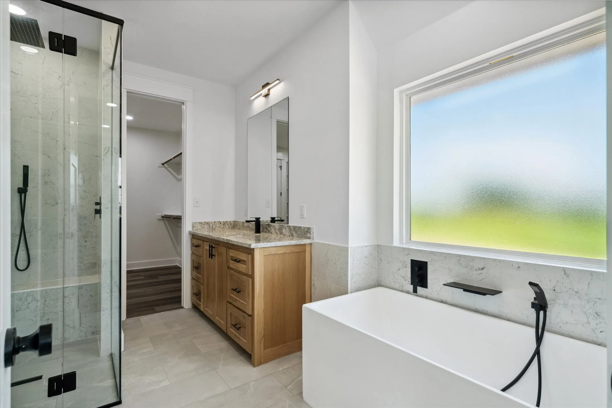 Bathroom featuring a marble finish shower, a freestanding bath, vanity, and a spacious closet