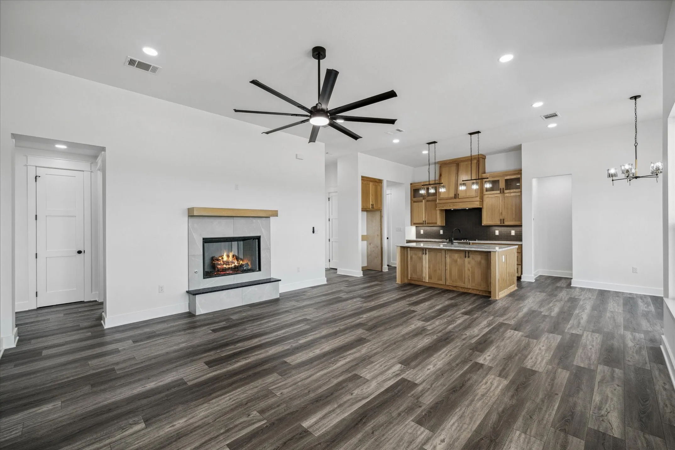 Unfurnished living room with ceiling fan, dark wood finished floors, a chandelier, recessed lighting, and a fireplace