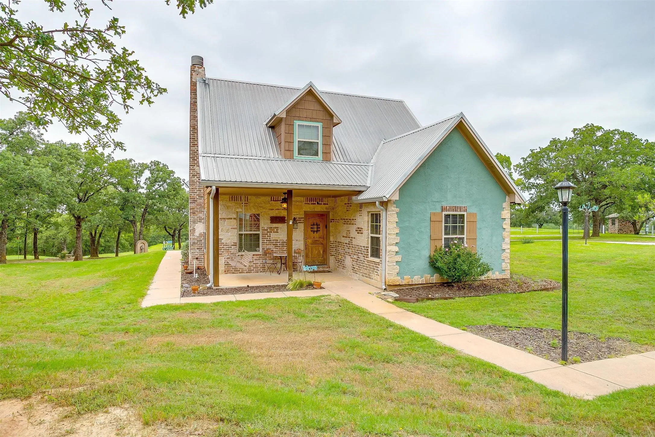 Still Water CABIN-View of front of home with a front yard, stucco siding, and a metal roof