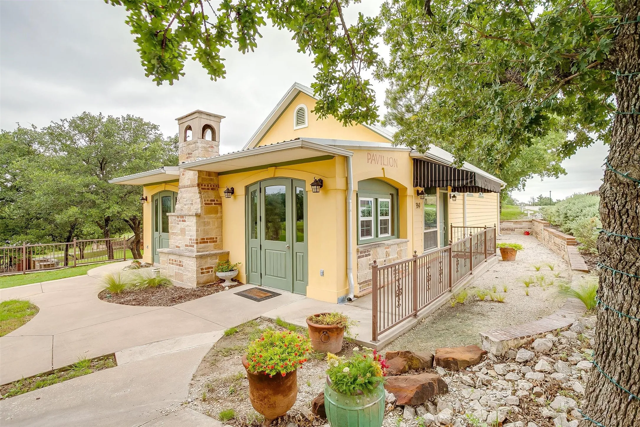 EVENT CENTER- Mediterranean / Spanish-style house with stucco siding and a chimney, fencing of cement walkway to Still Waters Cabin and Gazebo at the stocked pond.