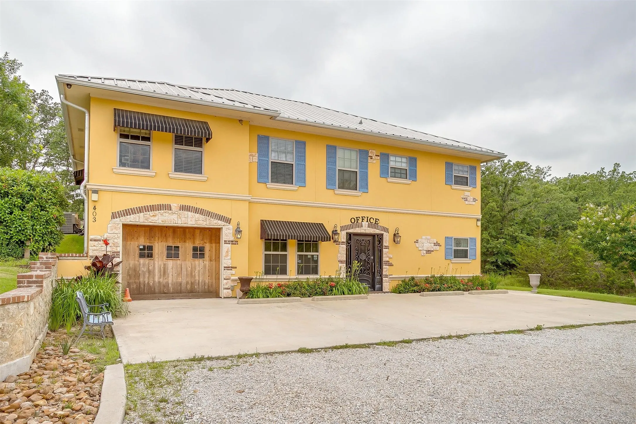 View of front electric double gate, cement driveway to primary building that holds primary residence and offices.