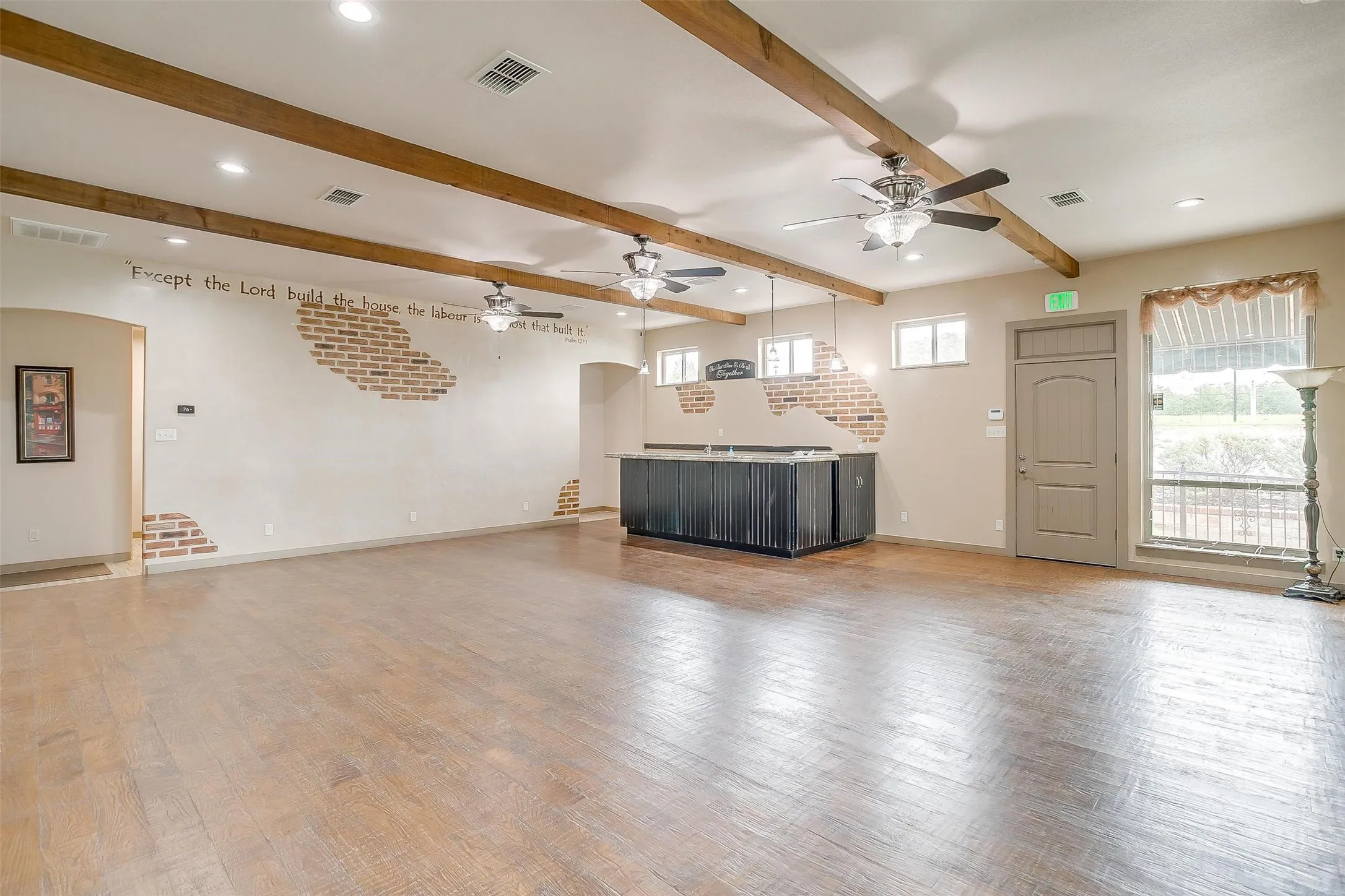 EVENT CENTER- featuring 1 of 2 fireplaces, tv, both bathroom doors, and both kitchen entrances, a ceiling fan, beam ceiling, light wood-type flooring, recessed lighting, and arched walkways, double entry into kitchen perfect for serving line for guest.