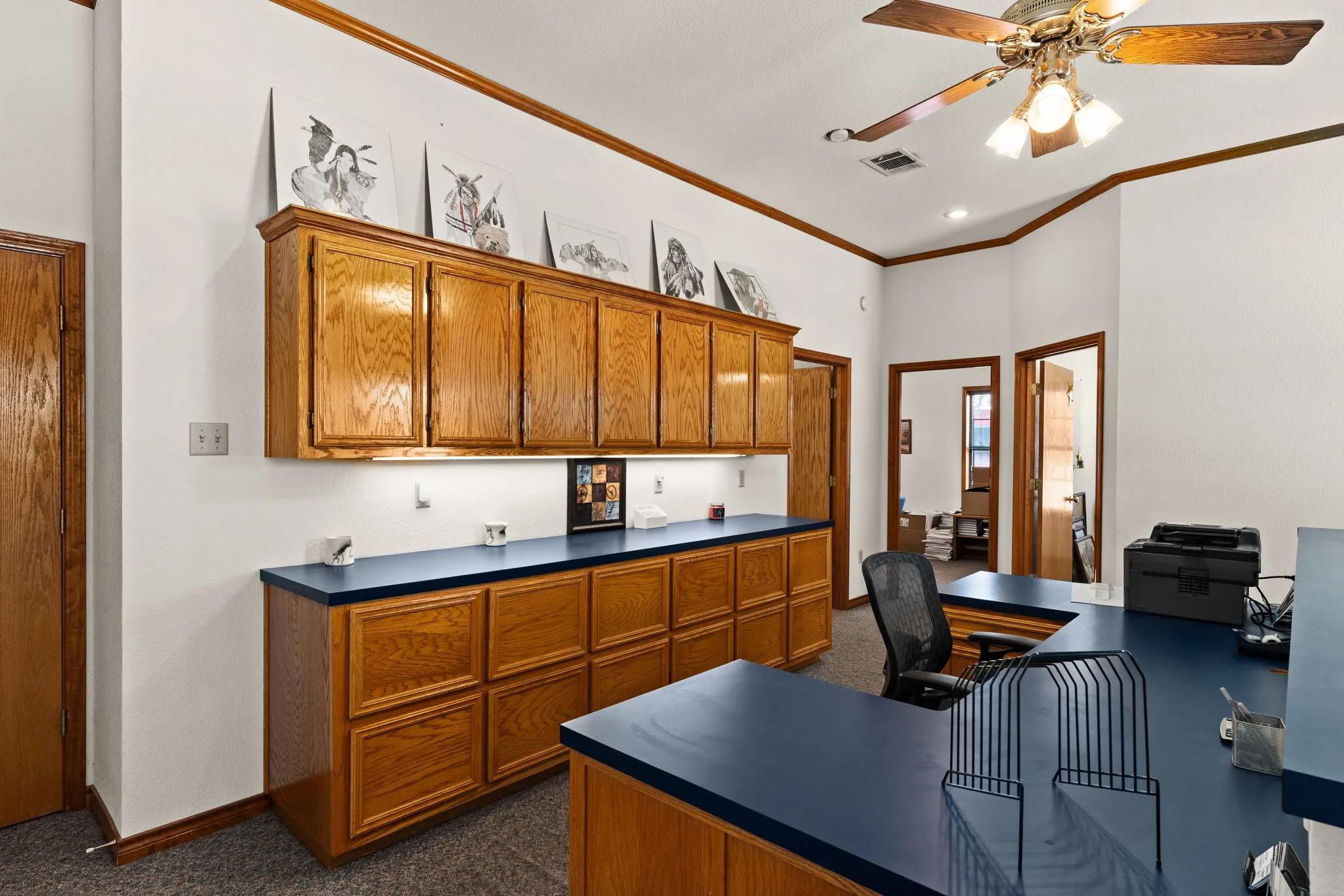 Home office with ornamental molding, dark colored carpet, and ceiling fan